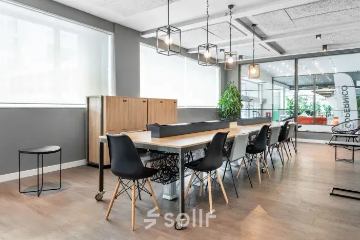 Moderne kantoorruimte met lange tafel en zwarte stoelen op Siriusdreef 17, Hoofddorp. Geschikt voor werkplekken met veel lichtinval door grote ramen. Ideaal om kantoorruimte te huren.