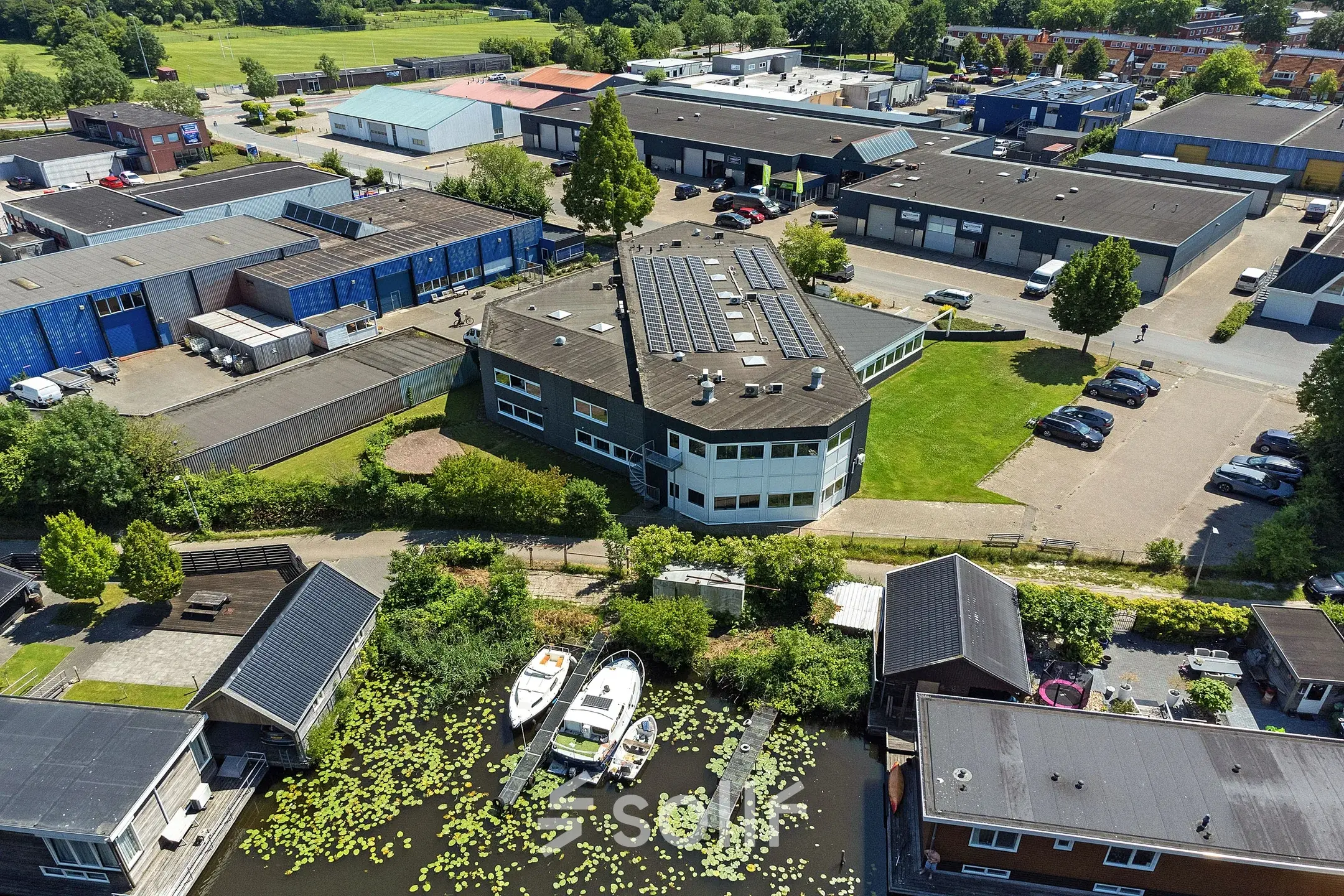 Luchtfoto van een kantoorpand aan de Ouddeelstraat 7a in Leeuwarden, omringd door groen en met parkeergelegenheid op het terrein. Ideaal voor kantoorruimte huren.