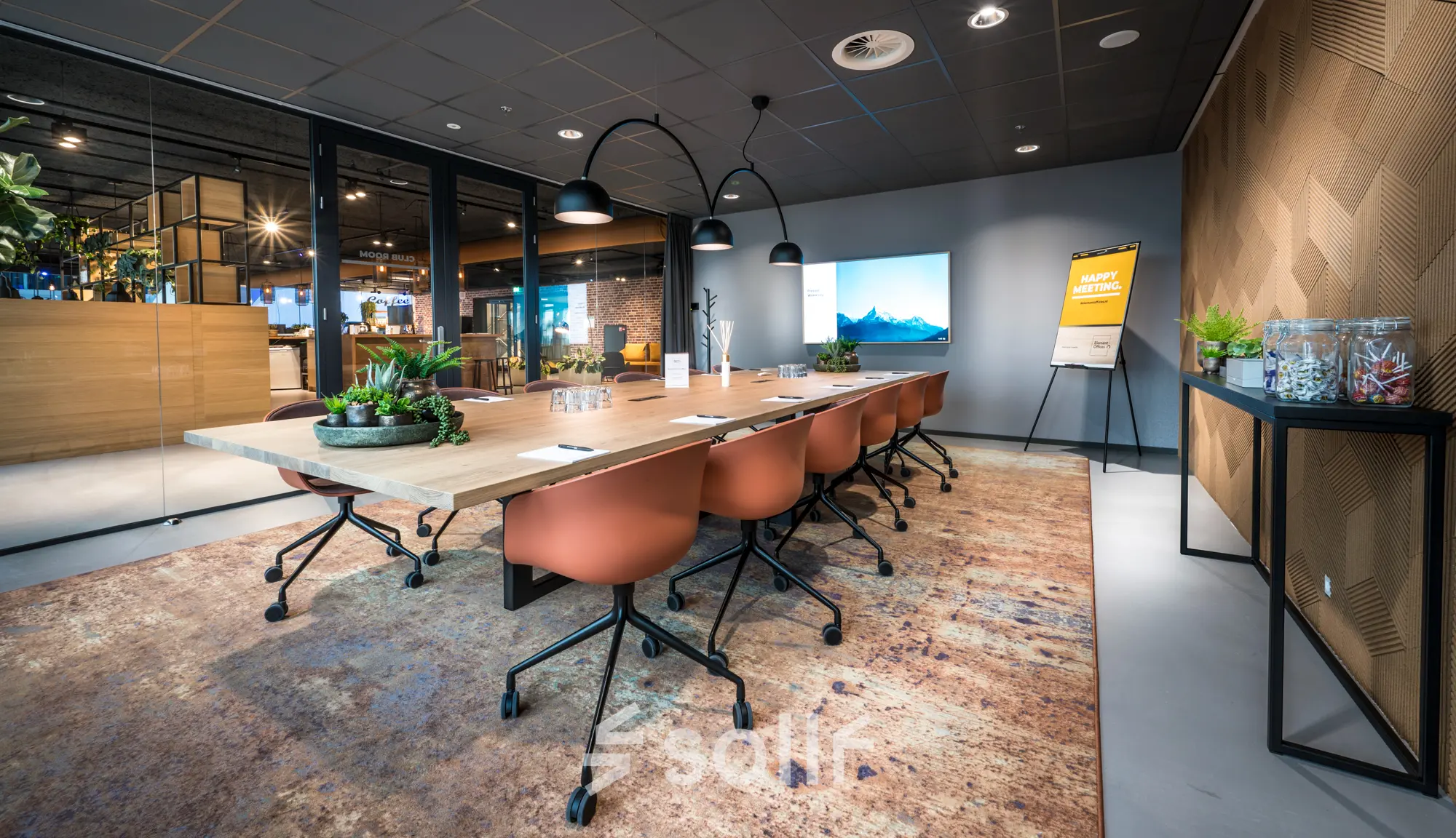 Moderne vergaderruimte in een kantoorpand op Bargelaan 200 in Leiden met houten tafel, oranje stoelen en sfeervolle verlichting.