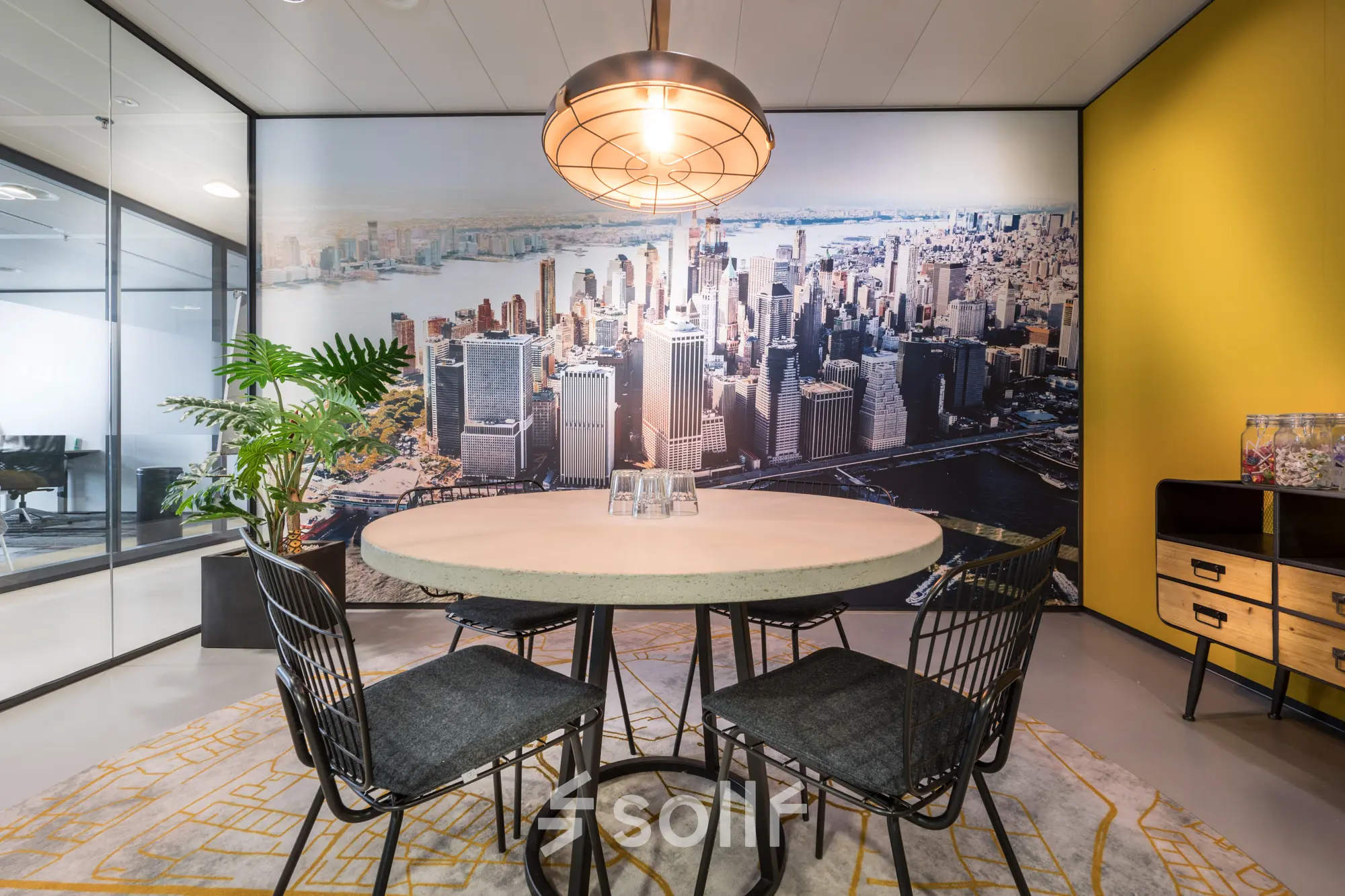 Kantoorruimte huren aan de Bargelaan 200 in Leiden met sfeervolle vergaderruimte, voorzien van ronde tafel, stoelen en stedelijke muurschildering voor een inspirerende werkomgeving in een modern kantoorpand.