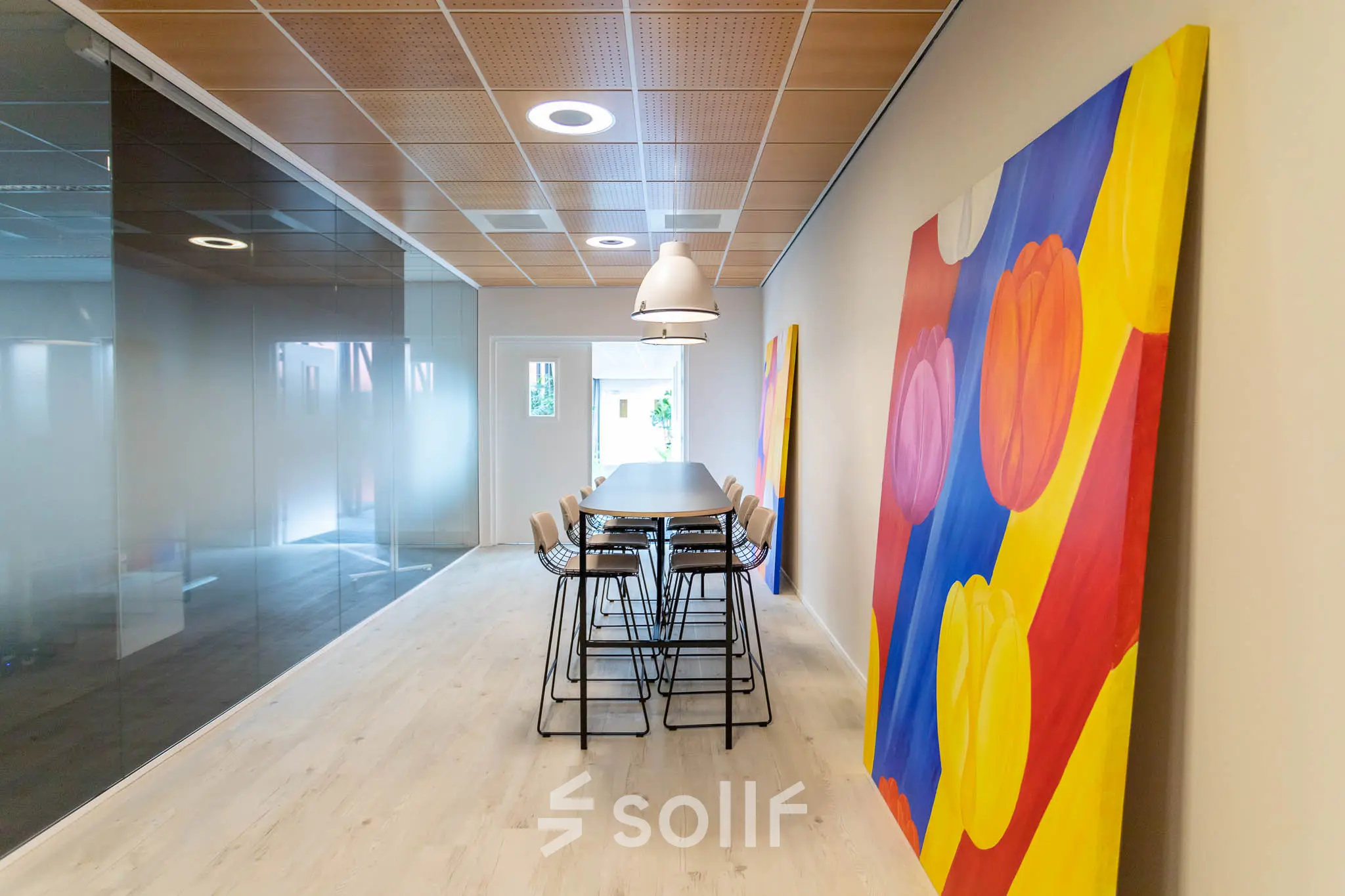 Modern kantoorpand op Pompoenweg 3 - 15 in Leiden met kleurrijke kunst, hoge stoelen en glazen wanden.