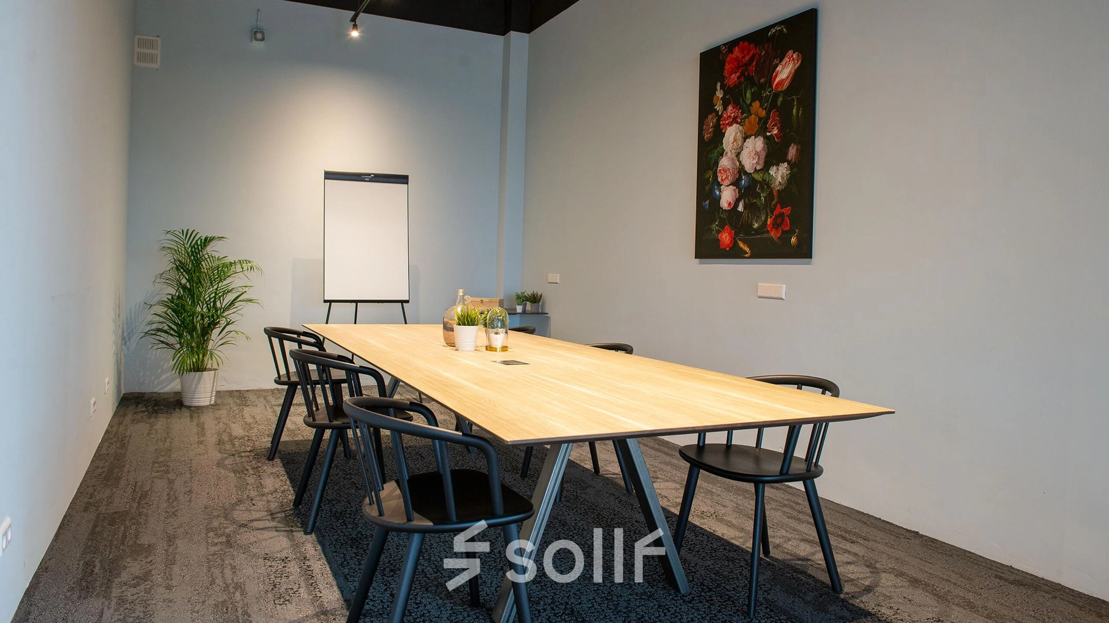Kantoorruimte huren in Meppel op Blankenstein 400 met een lange tafel omringd door stoelen, een flipover en planten, geschikt voor vergaderingen.
