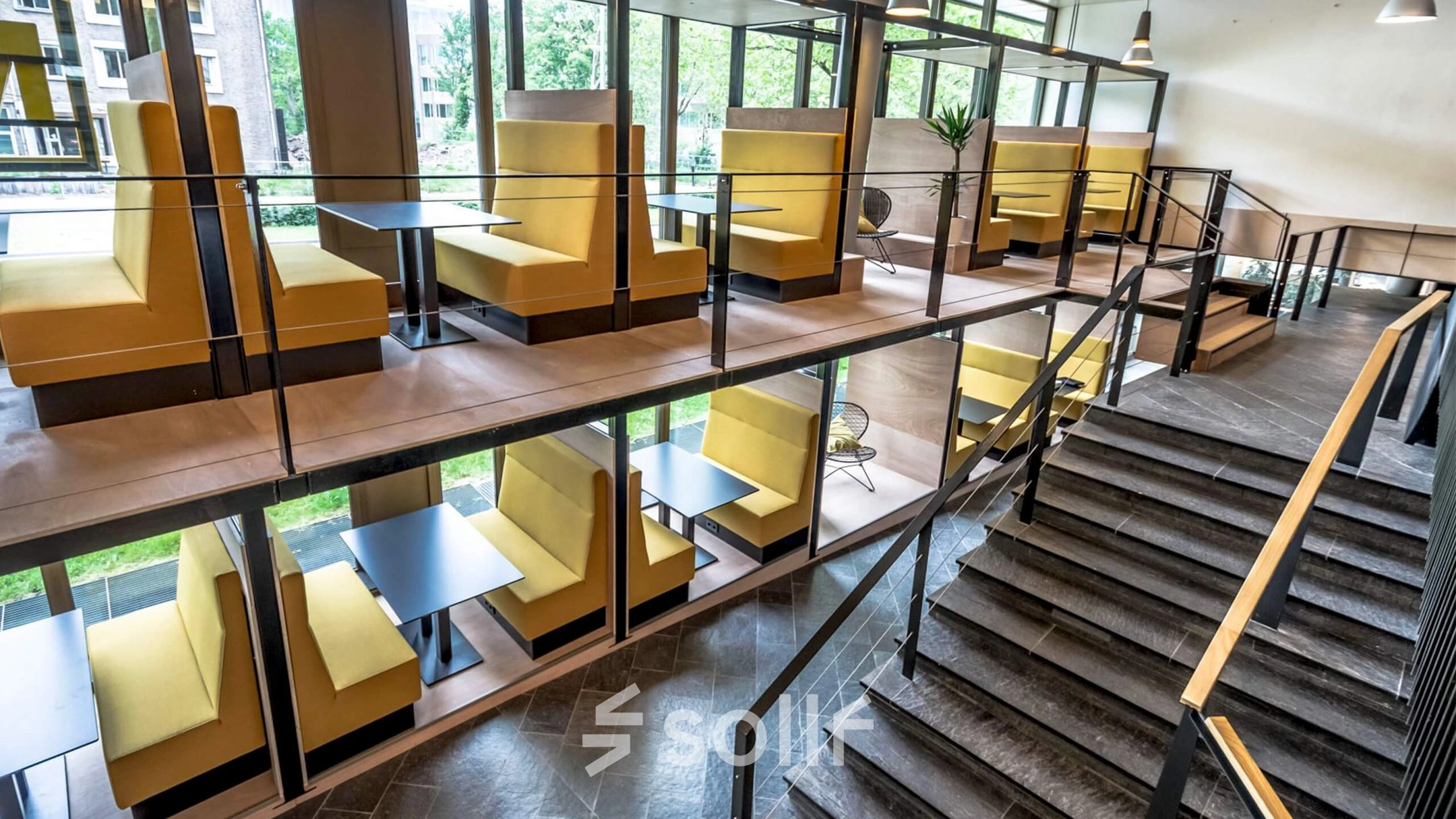 Moderne kantoorruimte in Meppel met meerdere werkplekken in gele cabines op twee niveaus, ideaal voor een creatieve werkomgeving. Grote ramen laten veel natuurlijk licht binnen.