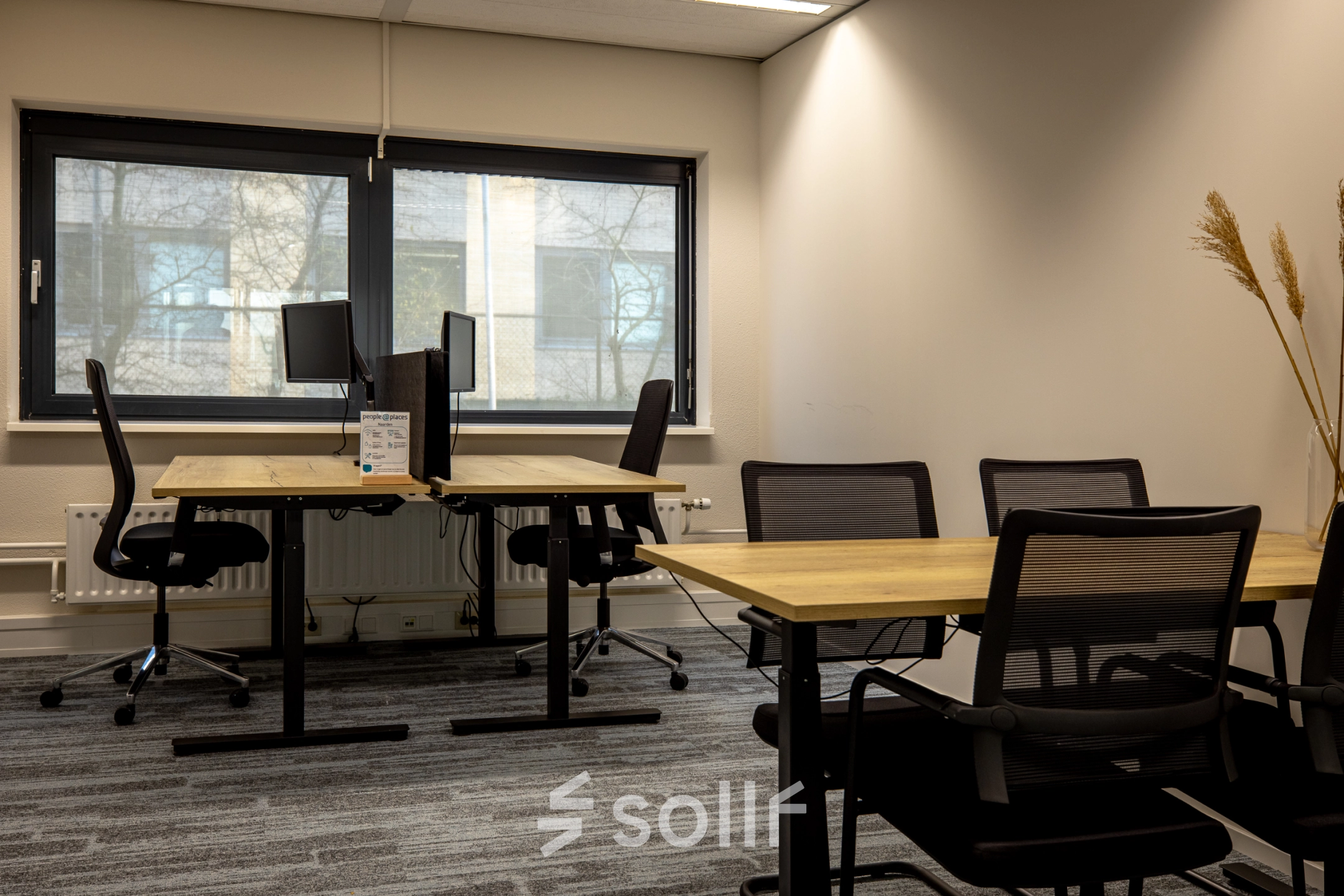 Kantoorruimte huren bij Gooimeer 1, Naarden: moderne werkplekken met houten bureaus en ergonomische stoelen, ideaal voor productief werk. Grote ramen zorgen voor natuurlijk licht.