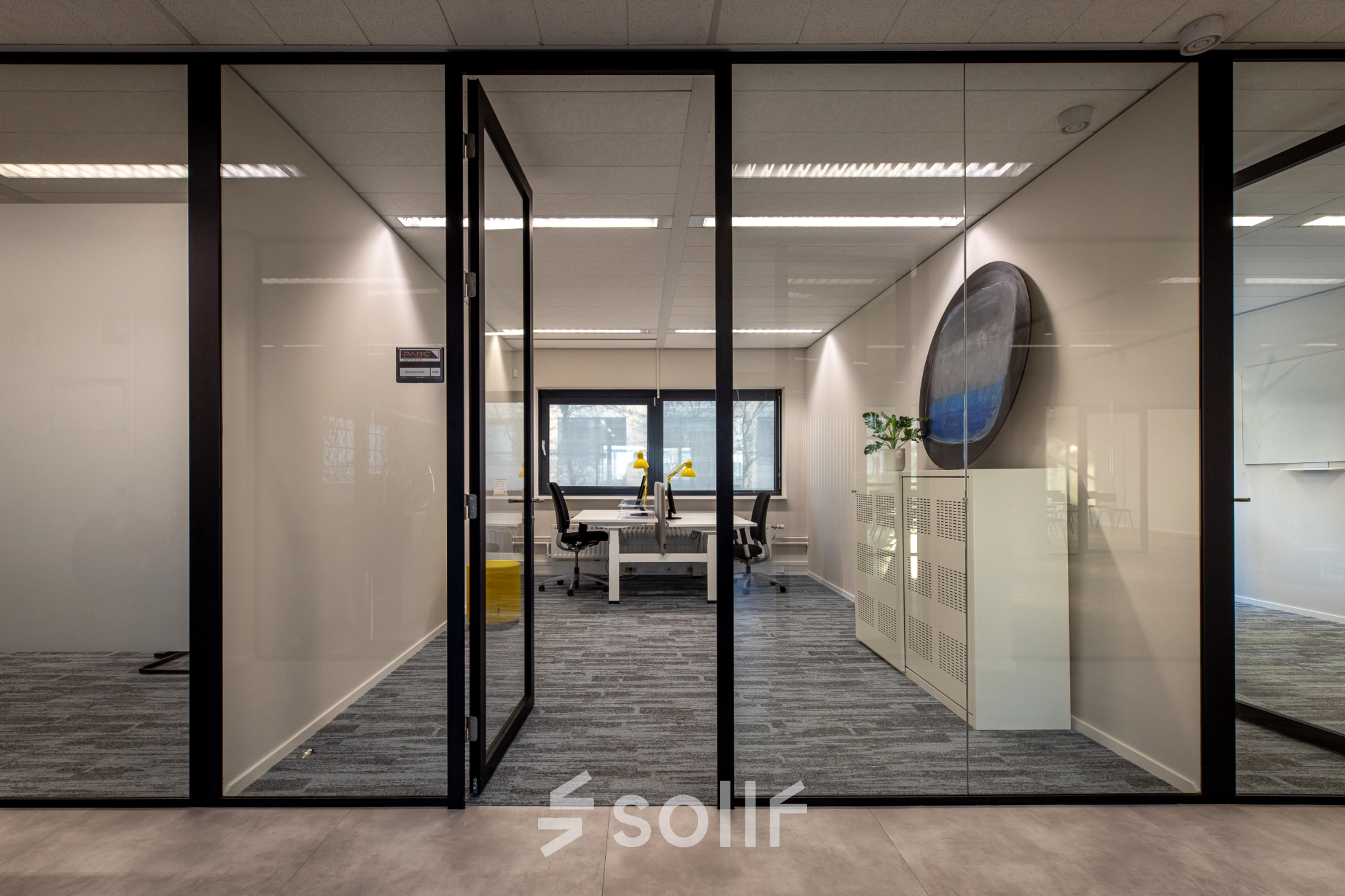 Moderne kantoorruimte huren in Naarden met glazen wanden, voorzien van bureaus en stoelen, gelegen aan Gooimeer 1.