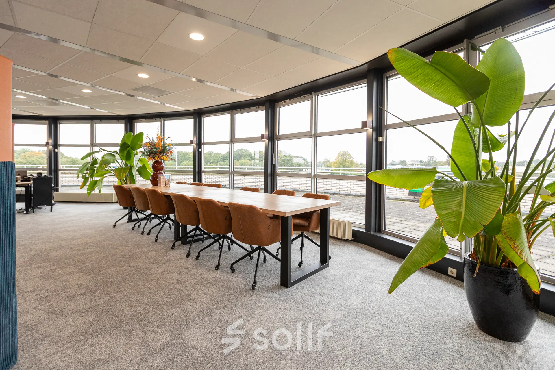 Lichte kantoorruimte met grote ramen, een lange tafel en stoelen, omgeven door planten, gelegen op Patroonstraat 13 in Nijkerk.