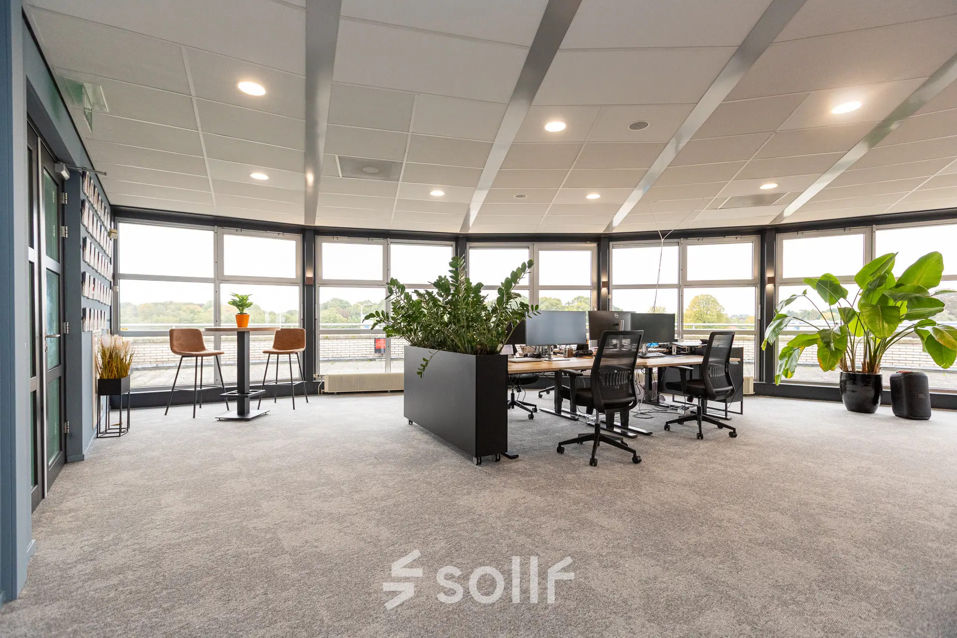 Ruime kantoorruimte met grote ramen en uitzicht, voorzien van bureaus en planten in een kantoorpand op Patroonstraat 13, Nijkerk.