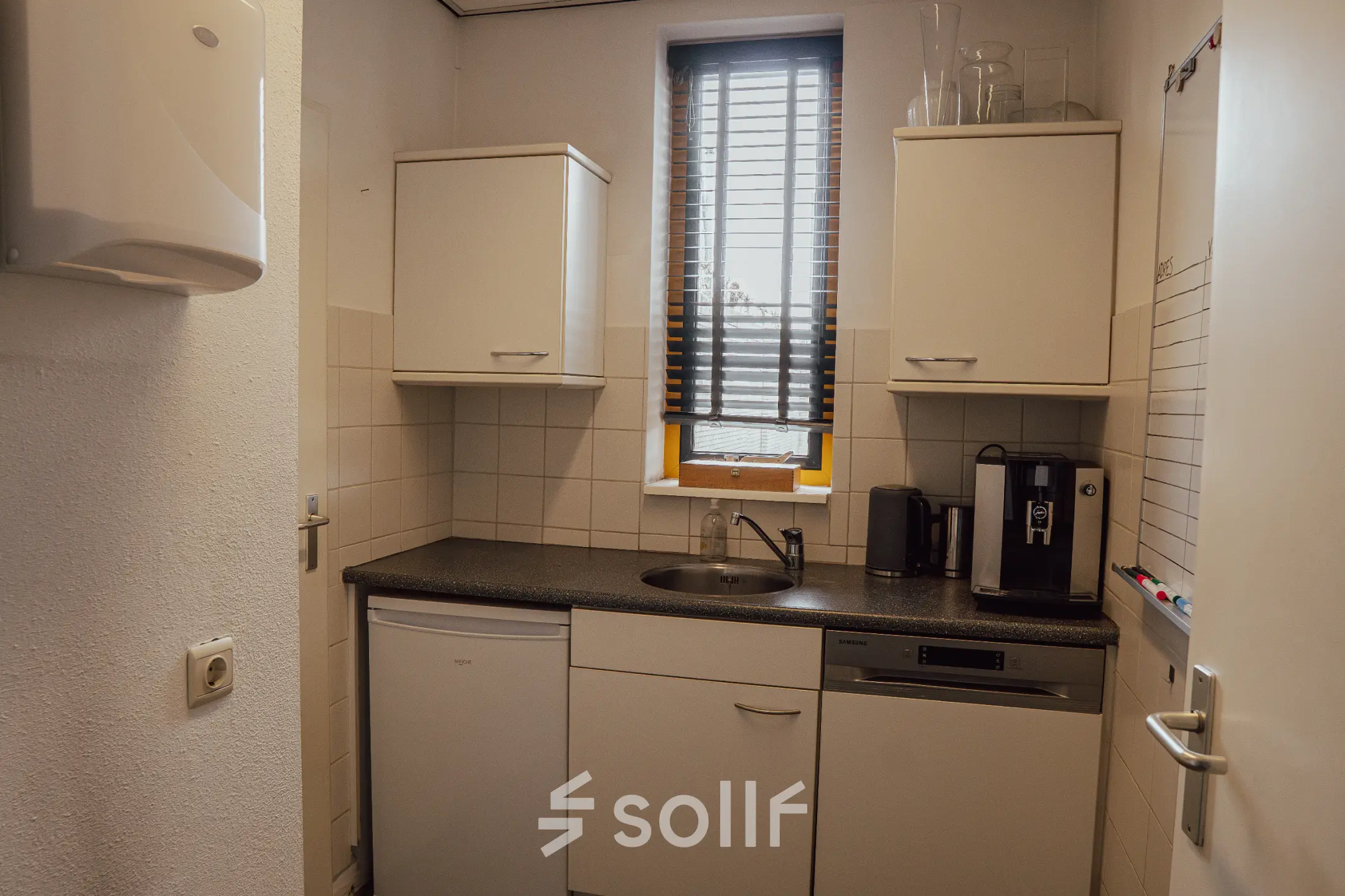 Compacte pantry met witte kasten, een gootsteen en een koffiezetapparaat in kantoorpand op Abdis van Thornstraat 74, Oosterhout Nb. Ideaal voor bedrijven die kantoorruimte huren en een functionele keuken wensen.