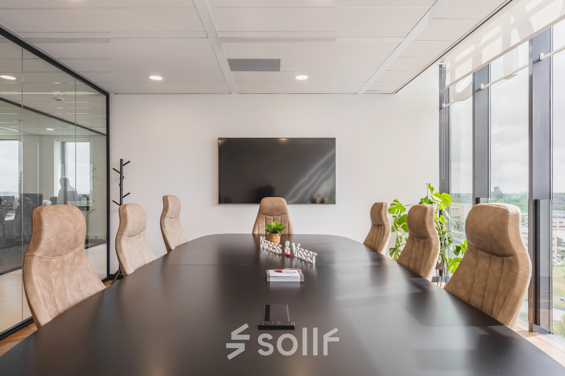 Moderne vergaderruimte in kantoorpand aan Laan van Zuid Hoorn 70, Rijswijk, met grote tafel, comfortabele stoelen, tv en veel lichtinval. Ideaal voor kantoorruimte huren.