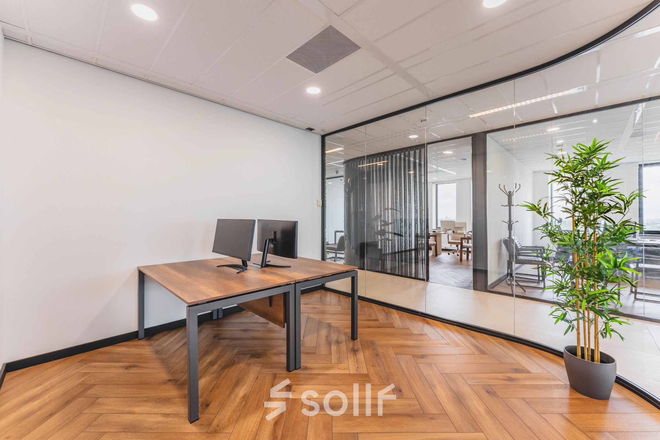 Moderne kantoorruimte te huur met glazen wanden, houten vloer en een bureau met monitor in Rijswijk.