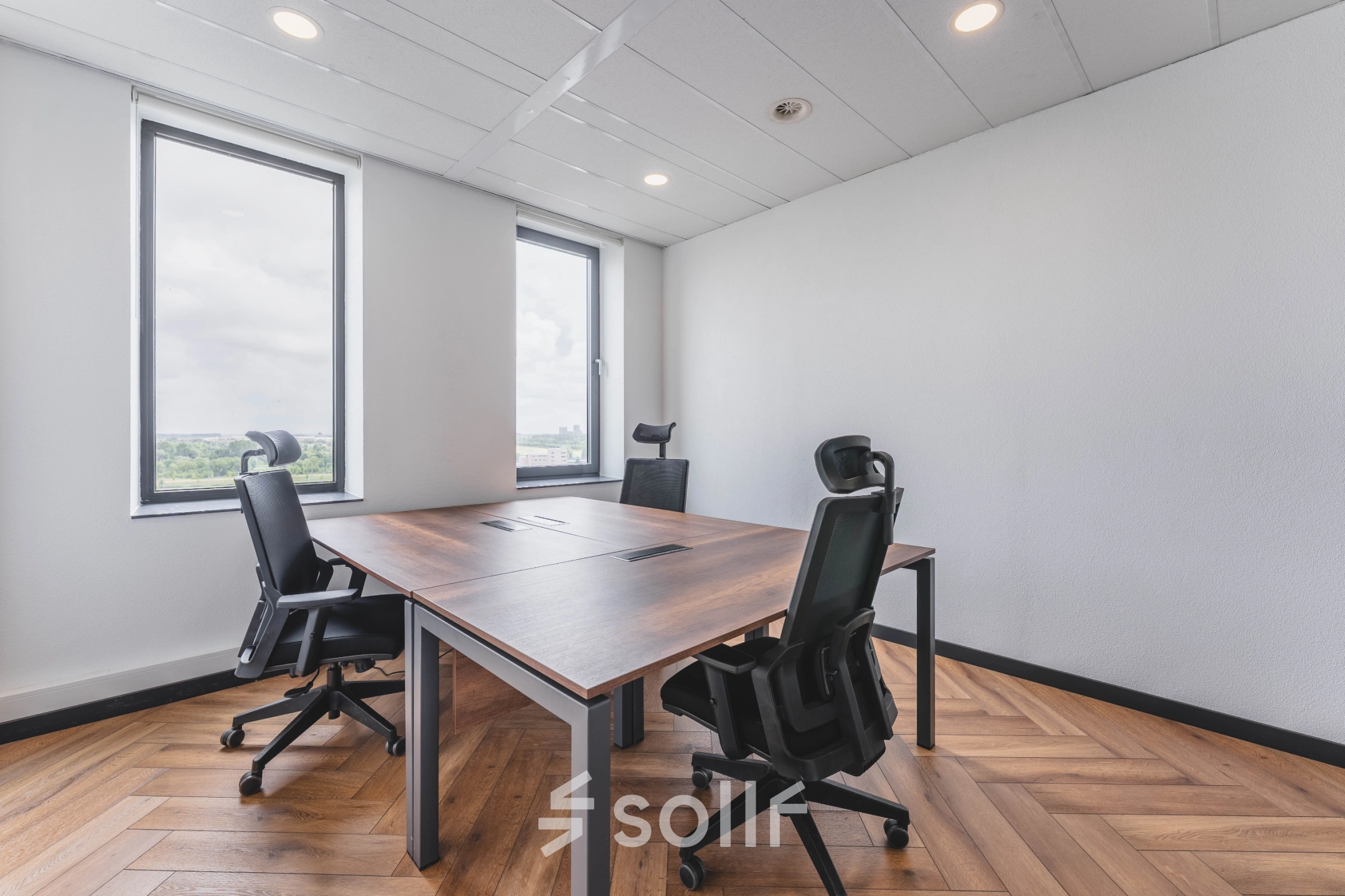 Lichte en moderne kantoorruimte met houten vloer en grote ramen, voorzien van vier bureaustoelen en een tafel, in Rijswijk.
