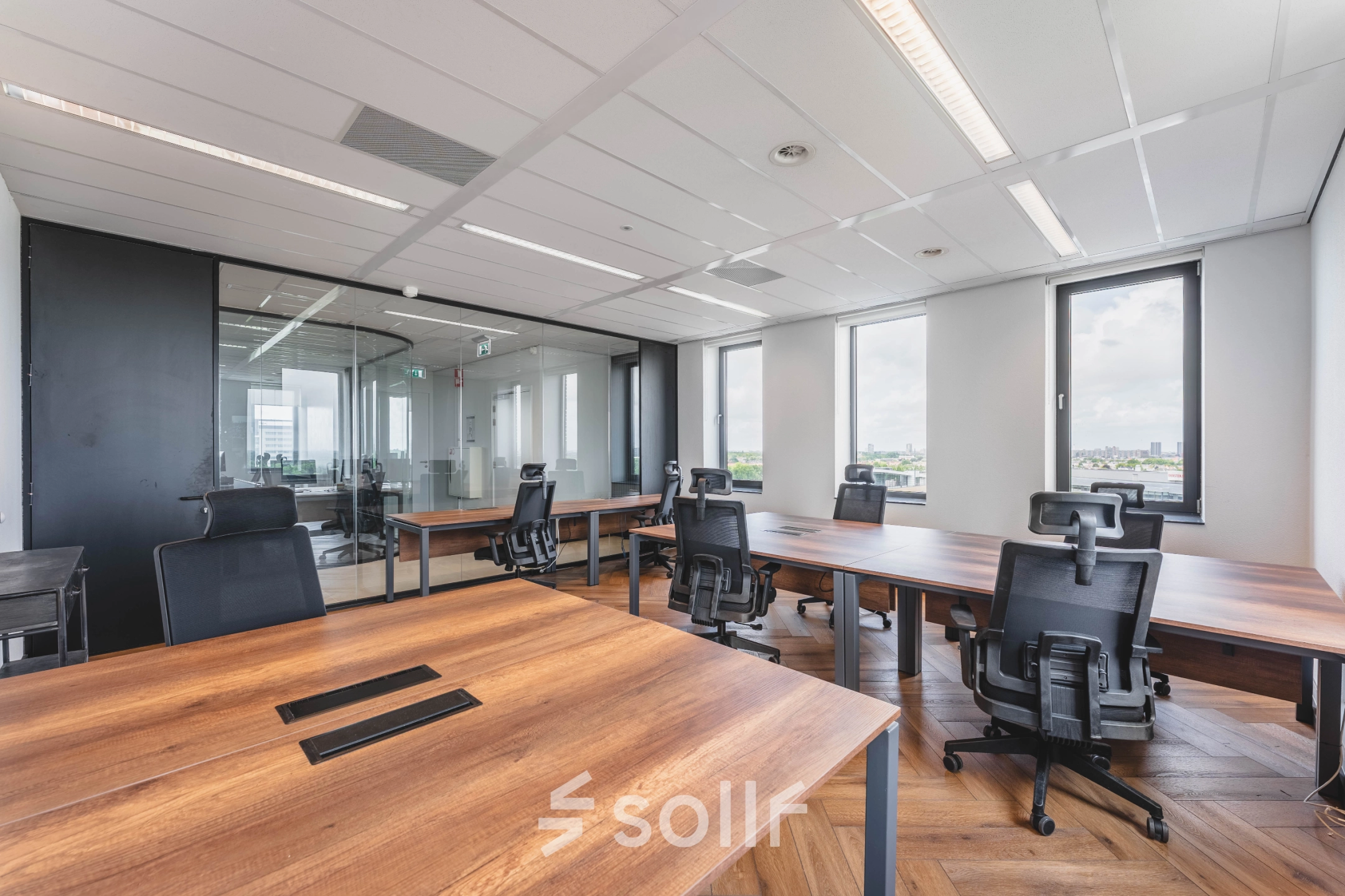 Kantoorruimte op Laan van Zuid Hoorn 70 in Rijswijk met grote ramen, houten bureaus en ergonomische stoelen, ideaal voor werkplekken.