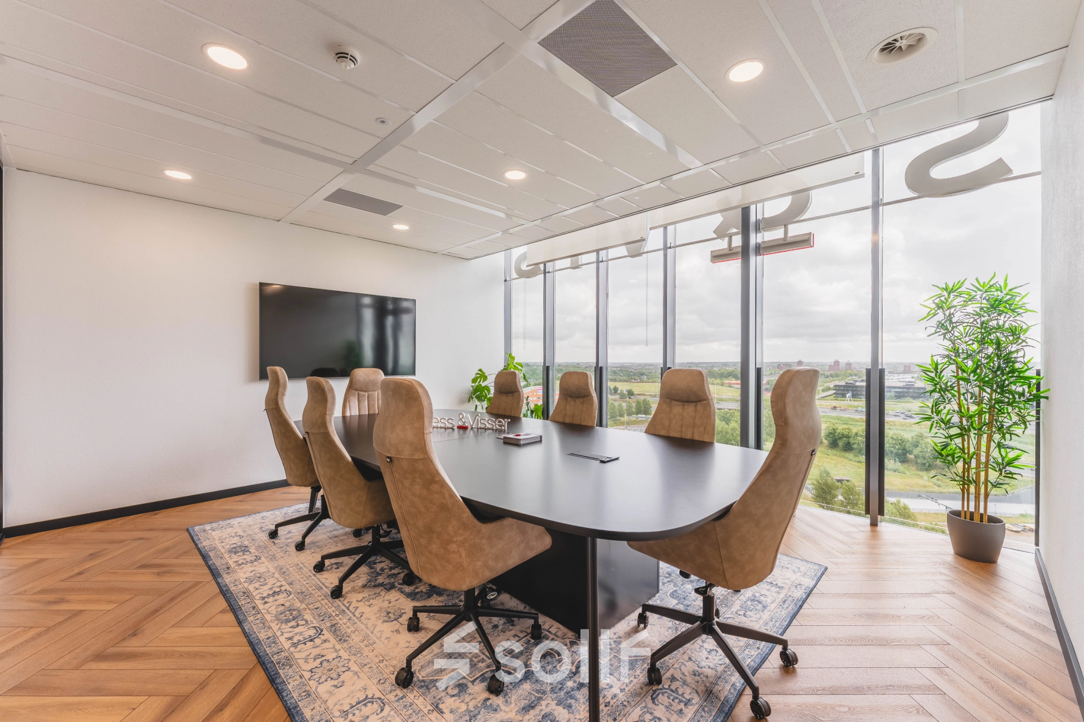 Vergaderruimte met een grote ovale tafel en comfortabele bruine stoelen in een kantoorpand aan de Laan van Zuid Hoorn 70, Rijswijk. De ruimte biedt een mooie blik naar buiten.