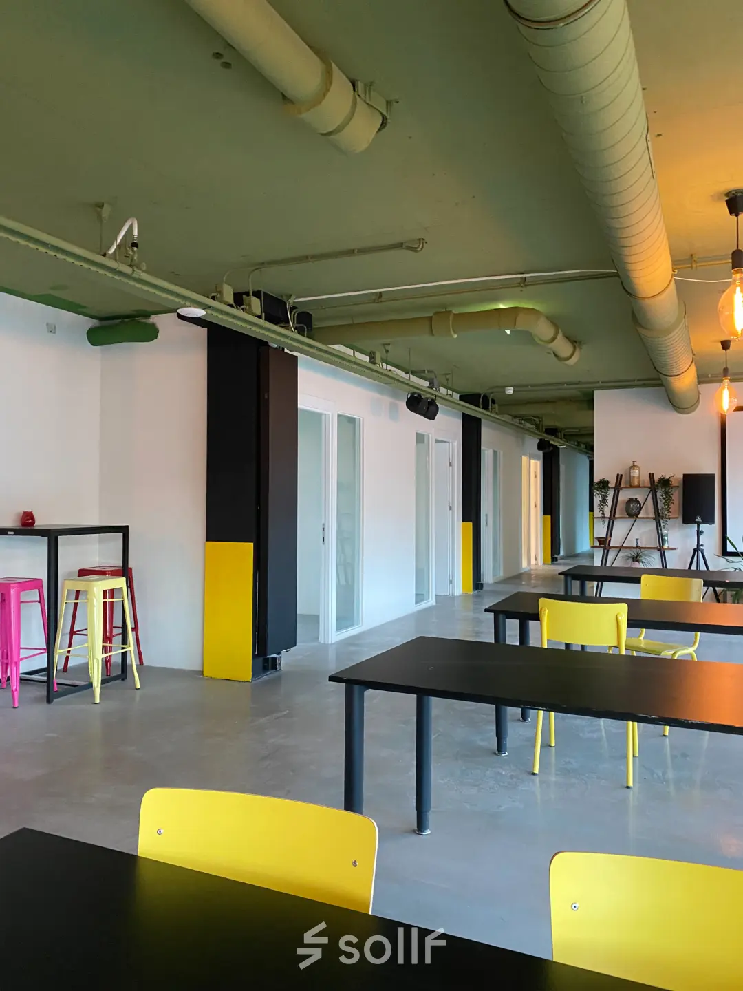 Moderne kantoorruimte te huur in Rijswijk, Volmerlaan 7, met kleurrijke stoelen en ruime werktafels ideaal voor een creatieve werkplek.