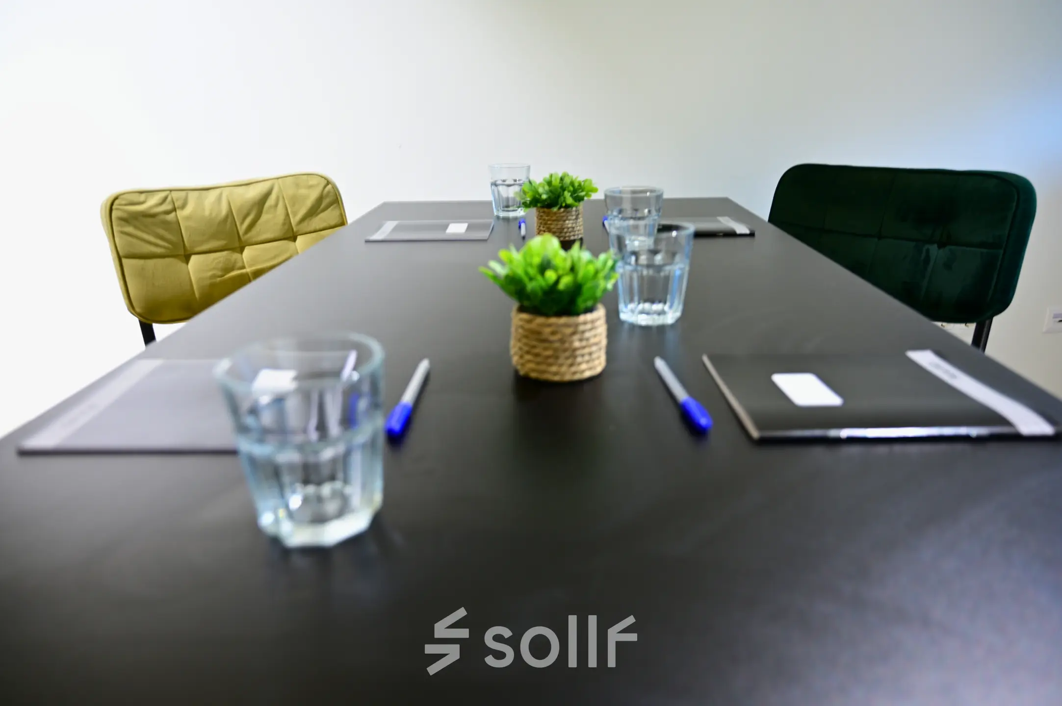 Vergaderruimte met een strakke tafel, glazen, pennen en notitieblokken, omringd door stijlvolle stoelen. Ideaal voor kantoorruimte huren aan Volmerlaan 7 in Rijswijk.