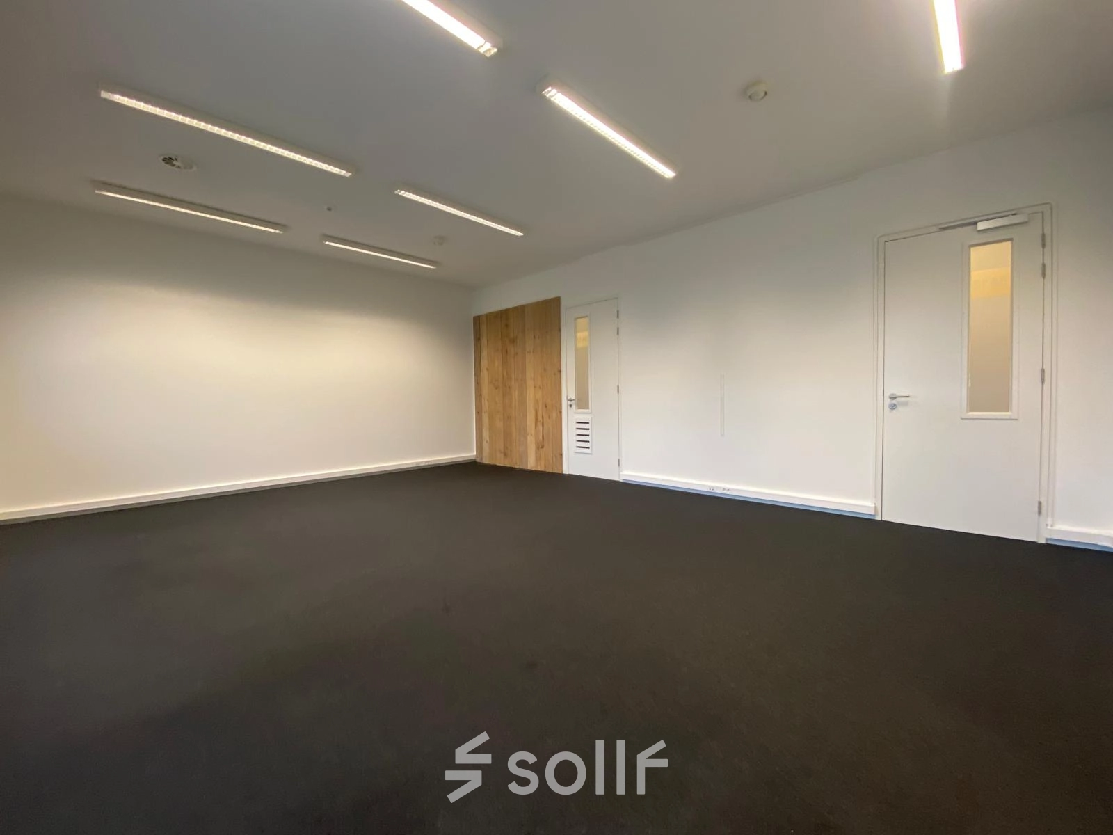 Leeg kantoorpand op Boven de Wolfskuil 3 in Roermond met witte muren en donkere vloerbedekking, perfect voor kantoorruimte huren.