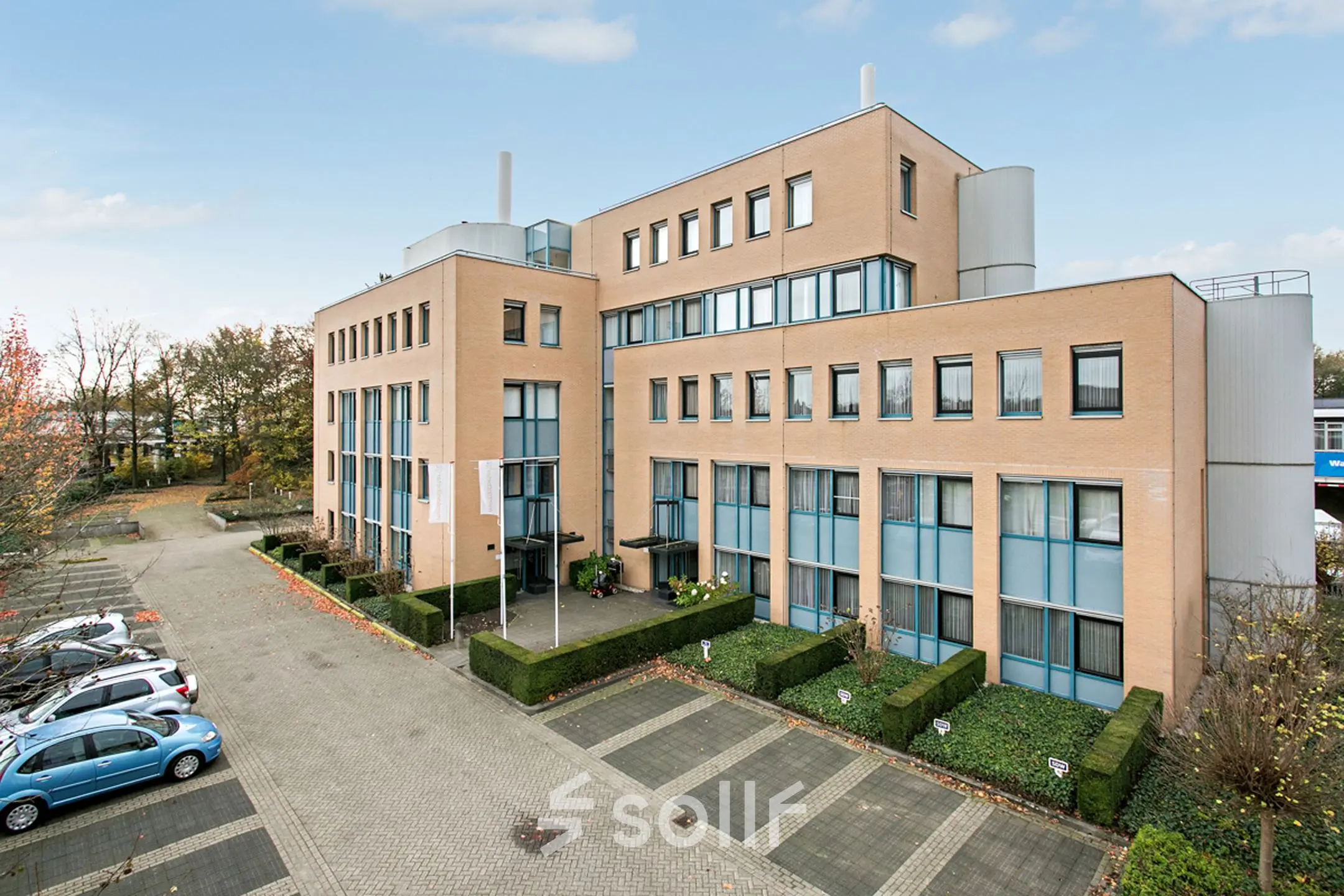 Uitzicht op modern kantoorpand aan Laan van Brabant 70-86 in Roosendaal, omgeven door parkeerplaatsen en groenvoorzieningen.