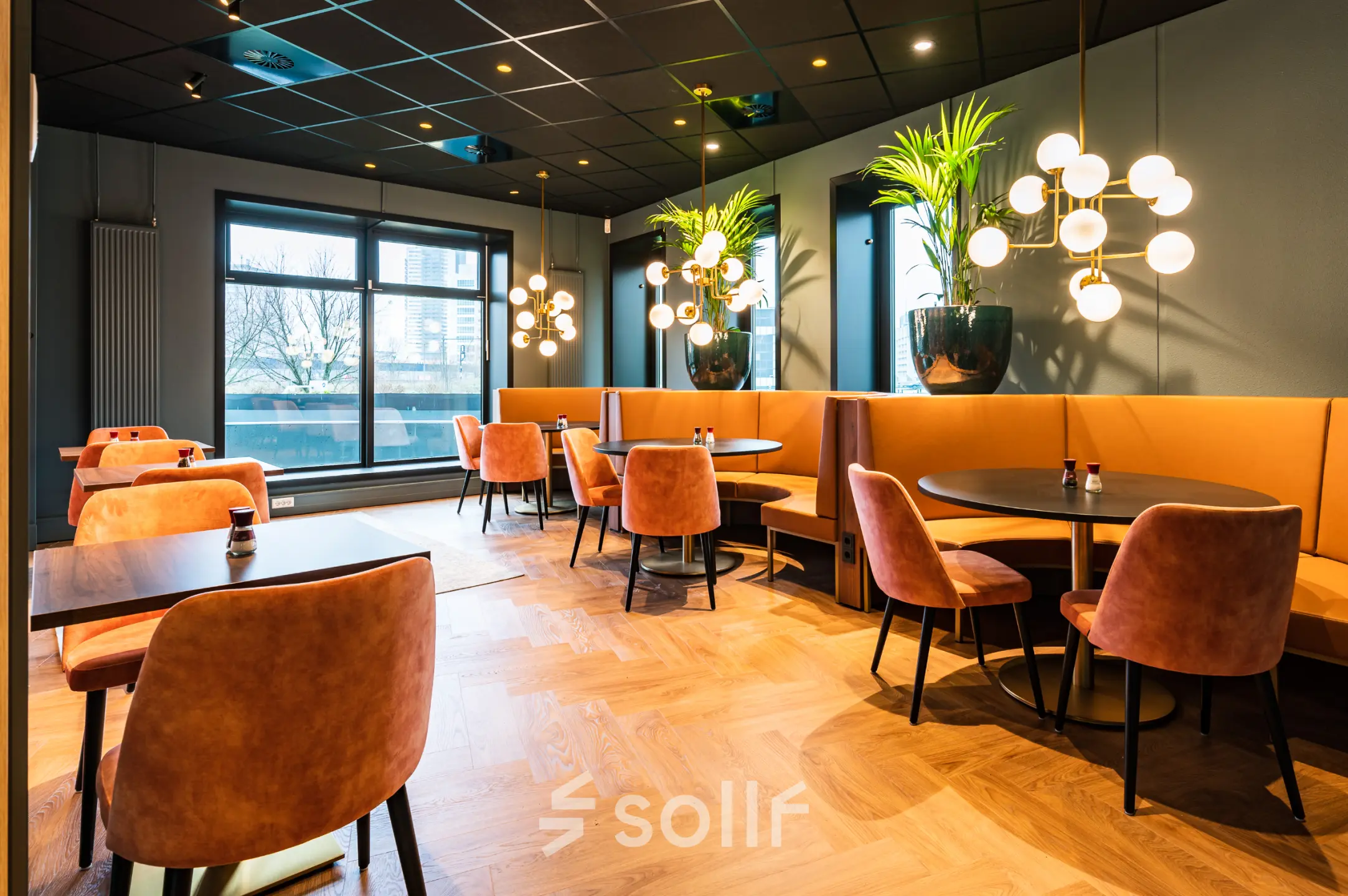 Moderne kantoorruimte huren in Rotterdam Alexander met stijlvolle tafels en stoelen, warme verlichting en grote ramen. Geschikt voor ontspannen werkplekken of vergaderingen.