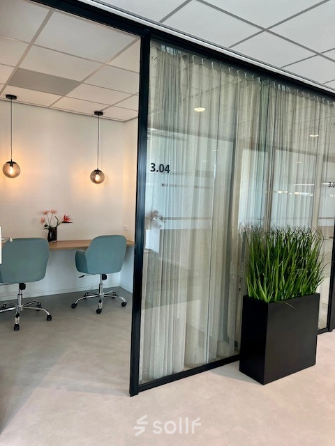 Moderne kantoorruimte huren in Rotterdam Brainpark met glazen wanden, een zitgedeelte met stoelen en een plant. Ideaal voor vergaderingen en werk in een rustige omgeving.