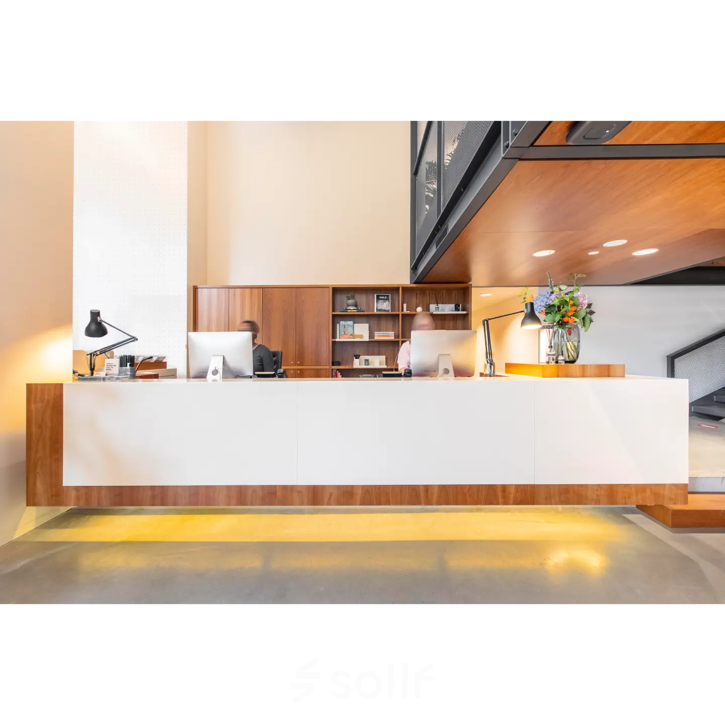 Moderne receptie in kantoorpand op Hofplein 20, Rotterdam Centraal Station. Twee mensen werken achter balie met computers en bloemen. Kantoorruimte huren met professionele uitstraling.