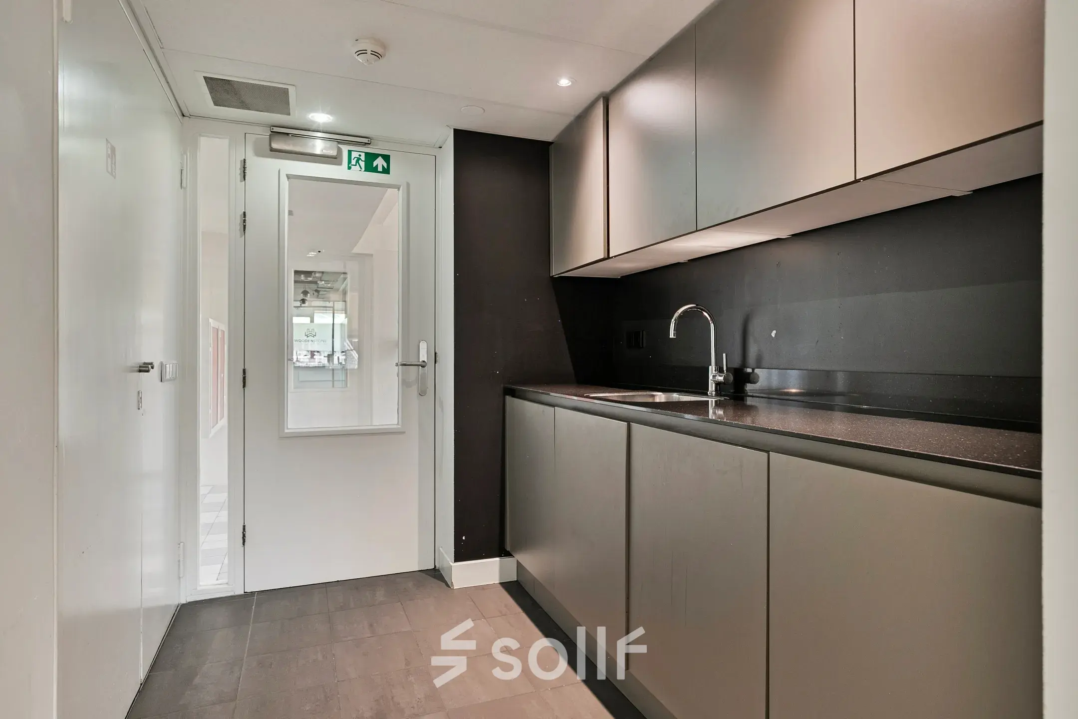 Moderne kitchenette in een kantoorpand aan Coolsingel 104, Rotterdam Centrum. Ideaal voor huur, met strakke grijze kasten en een donkere werkblad voor functies als kantoorruimte huren.