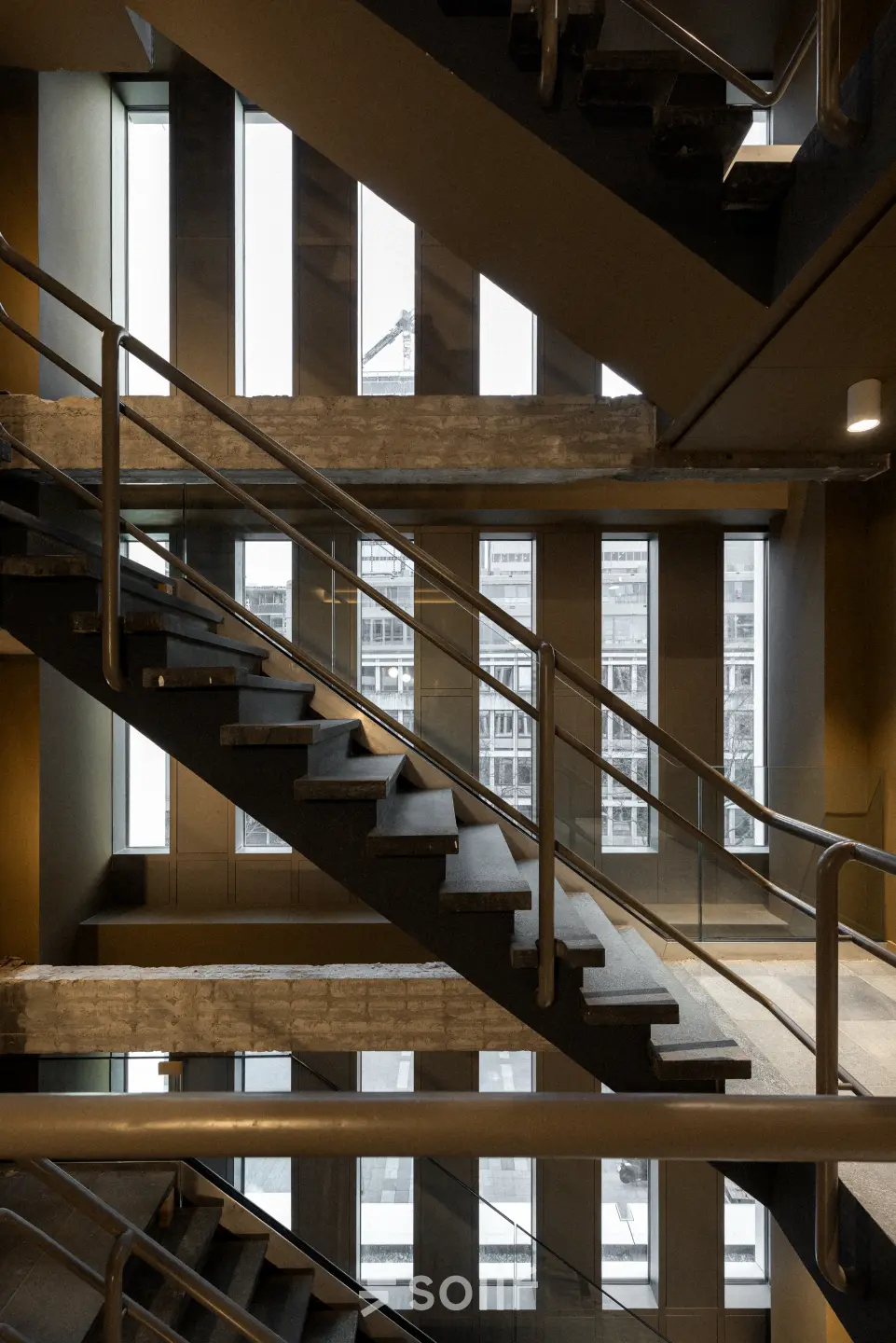 Moderne trap in het kantoorpand op Stadhuisplein 9-23, Rotterdam Centrum met veel natuurlijk licht door grote ramen.