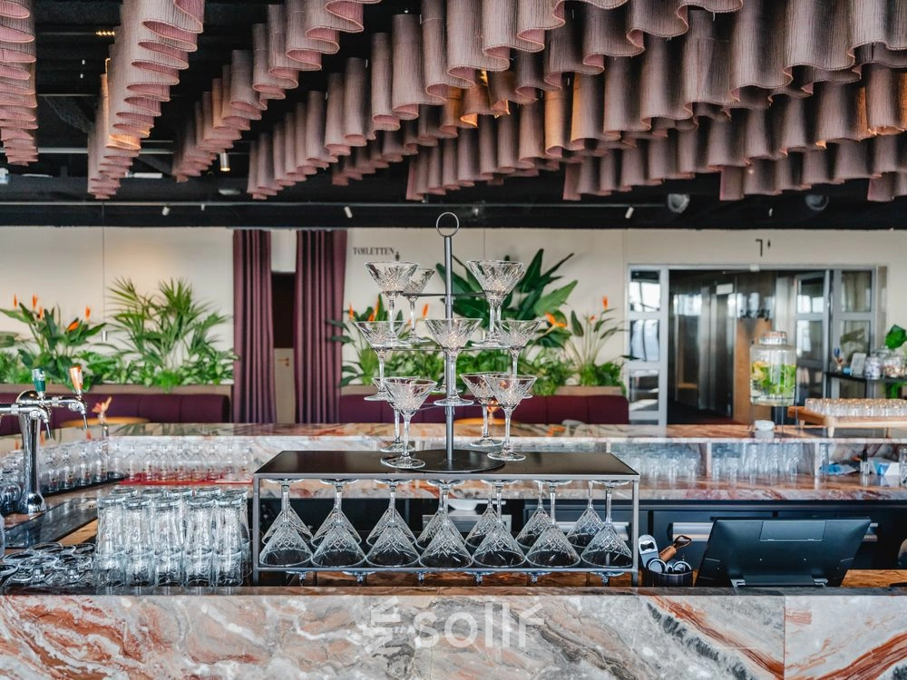 Chique kantoorpand op Weena 690 in Rotterdam Centrum met een elegant ingerichte bar en planten die de ruimte een levendige sfeer geven. Perfect voor kantoorruimte huren.