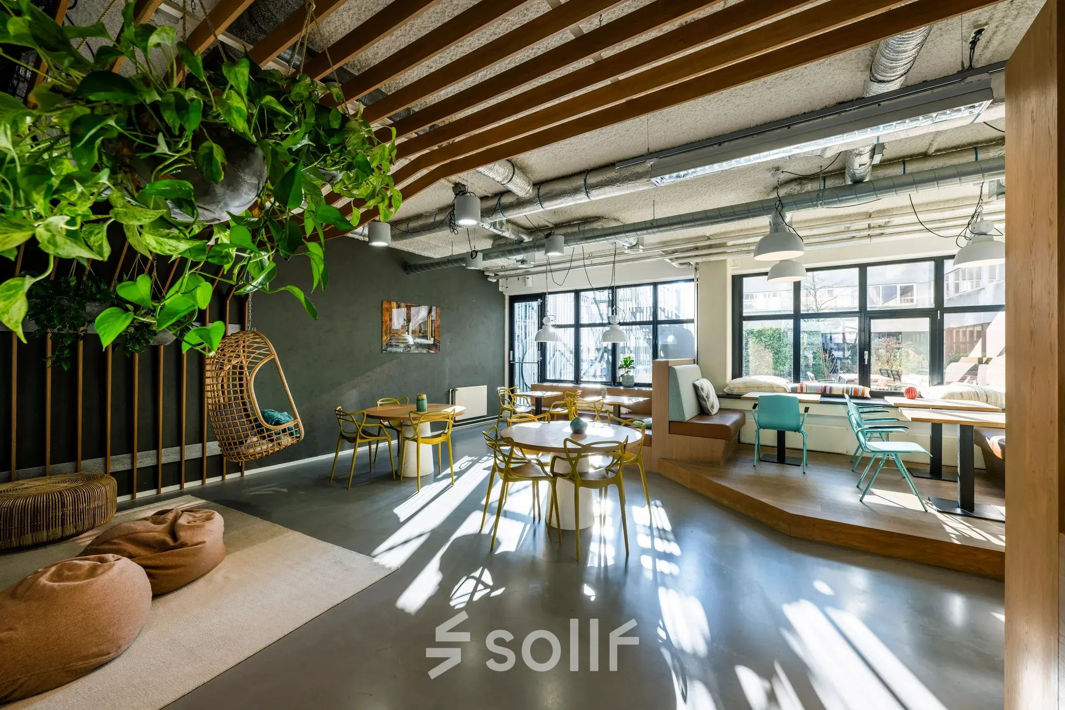 Moderne kantoorruimte aan de Westblaak 180 in Rotterdam Centrum, met veel natuurlijk licht en een stijlvolle inrichting met hangplanten en diverse zitplekken. Ideaal voor het huren van inspirerende werkplekken.
