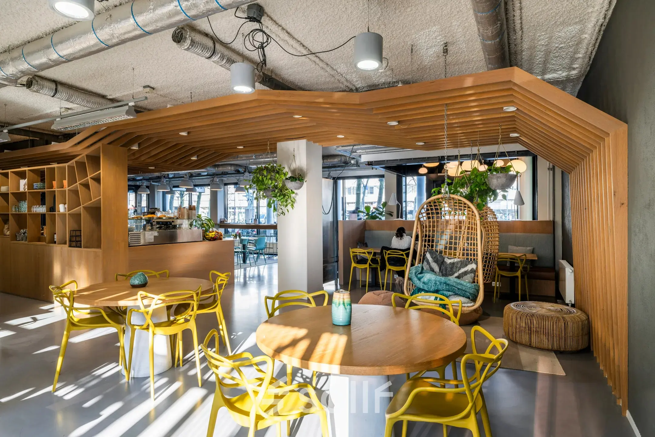 Moderne kantoorruimte in Rotterdam Centrum op Westblaak 180 met houten en gele accenten, geschikt om te huren. Gezellige inrichting met planten en tafels. Ideale plek voor creatieve werksessies.