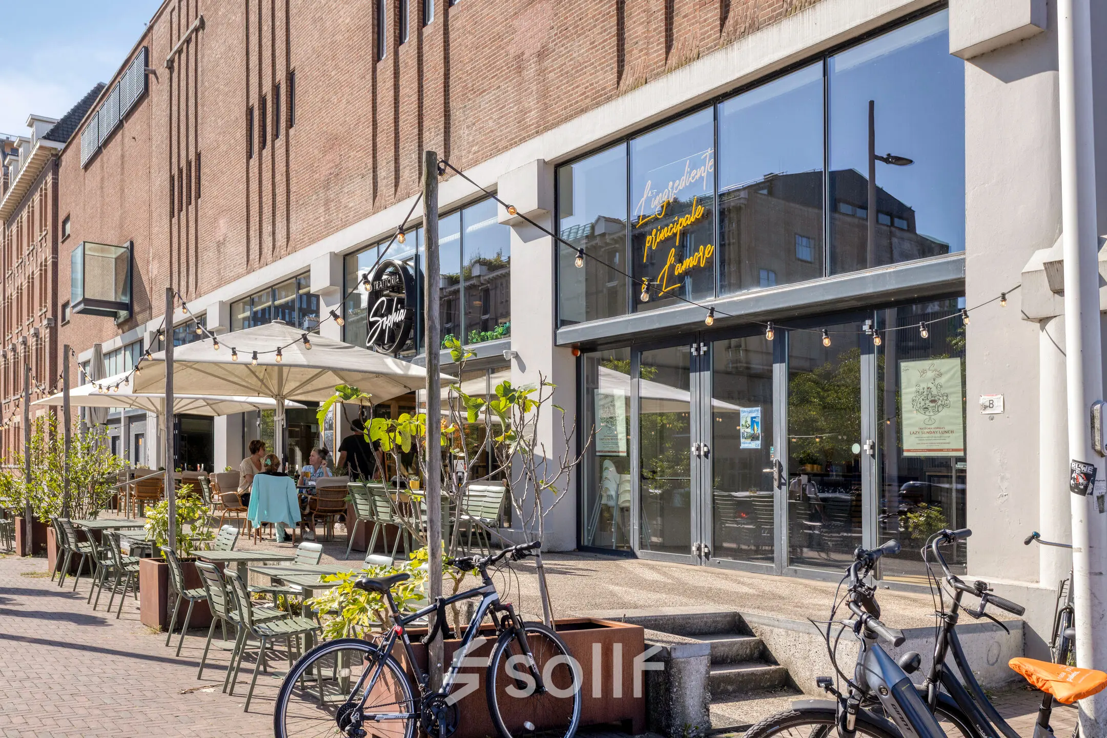 Buitenzijde van een pand aan de Lloydstraat 21 B in Rotterdam Delfshaven met terrassen en enkele fietsen op de voorgrond, ideaal voor kantoorruimte huren.