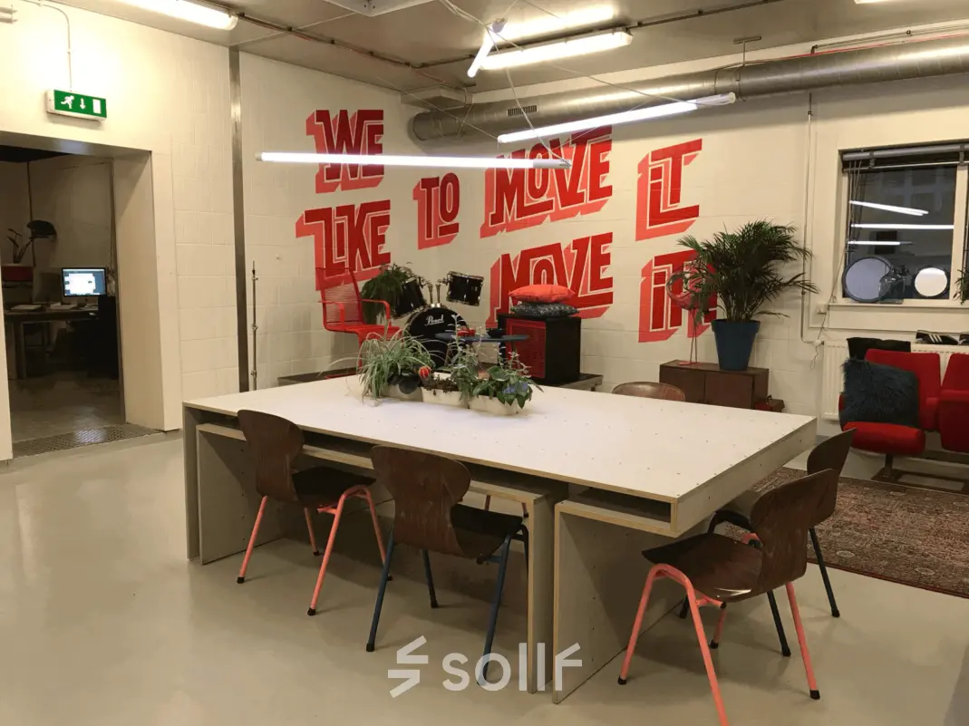Moderne kantoorruimte huren in Rotterdam Delfshaven, met stijlvolle meubels en inspirerende muurtekening. Ideaal voor creatieve meetings en samenwerking.