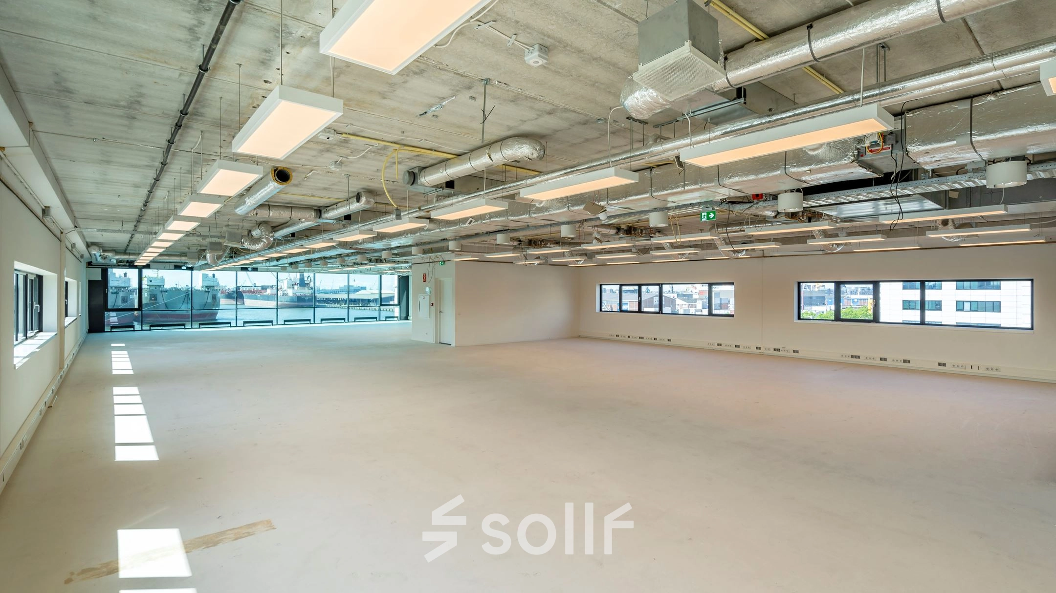 Ruime, lichte kantoorruimte in Rotterdam Waalhaven met grote ramen en modern industrieel plafond, ideaal voor het huren van diverse kantooropstellingen.