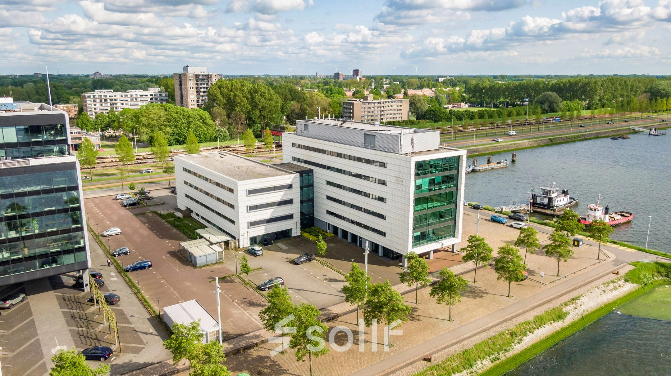 Luchtopname van een modern kantoorpand aan Waalhaven O.z. 85 in Rotterdam Waalhaven, met parkeerplaatsen en groene omgeving. Kantoorruimte huren in een stedelijke setting nabij het water.