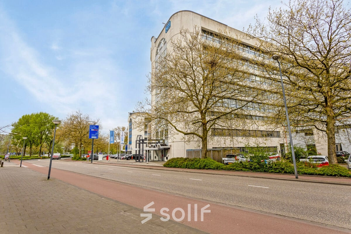 Buitenaanzicht van kantoorpand aan de Brauwweg 52-66 in Schiedam, met moderne architectuur omgeven door bomen en geparkeerde auto's.