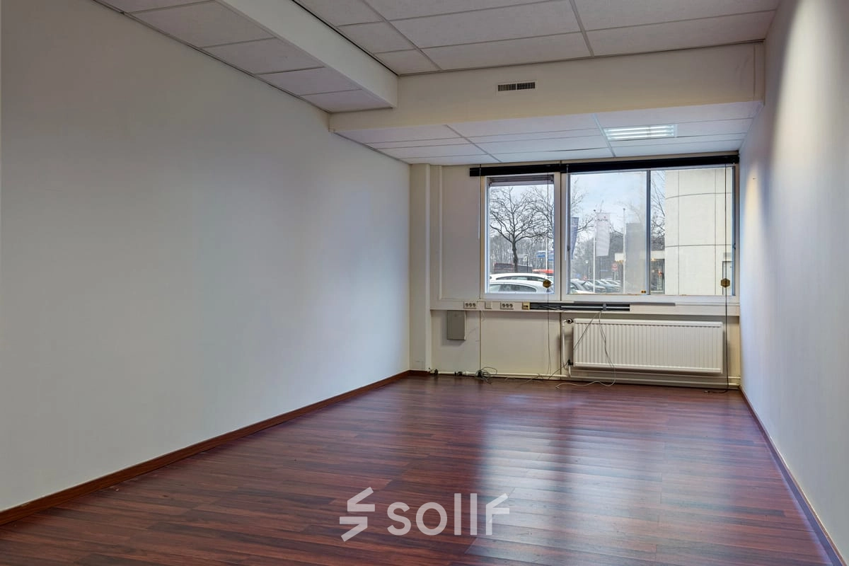 Ongemeubileerde kantoorruimte op de Brauwweg 52-66 in Schiedam met houten vloeren en een raam met uitzicht naar buiten.
