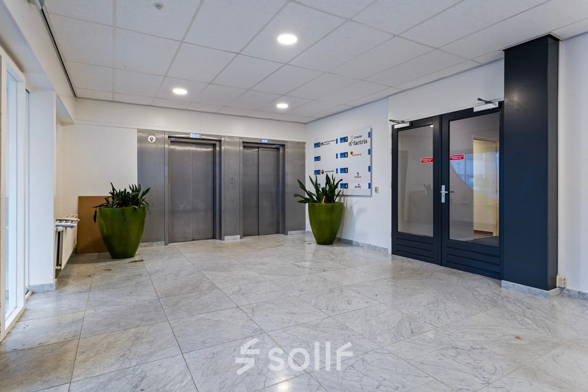 In de entree van het kantoorpand op de Brauwweg 52-66 in Schiedam zijn liften en glazen deuren te zien, met sierplanten voor een uitnodigende sfeer. Ideaal voor kantoorruimte huren.