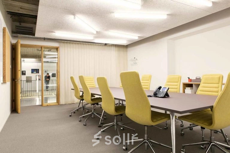 Moderne vergaderruimte in kantoorpand Schiphol Airport met gele stoelen rond een grote tafel, geschikt voor kantoorruimte huren.