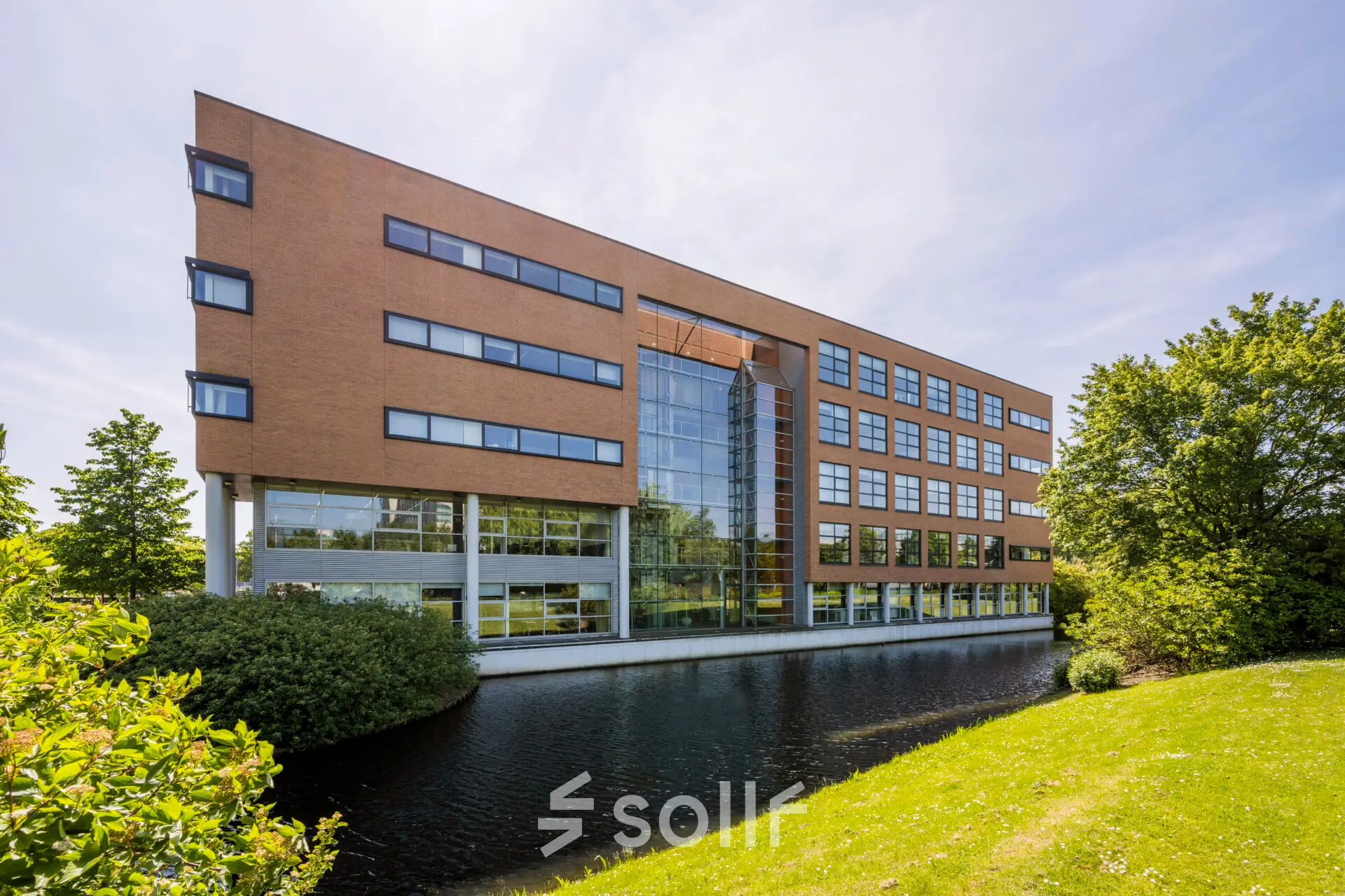 Buitenzijde van een modern kantoorpand aan Boeing Avenue 1-19 in Schiphol Rijk, omgeven door groen en een waterpartij. Ideale locatie voor kantoorruimte huren.