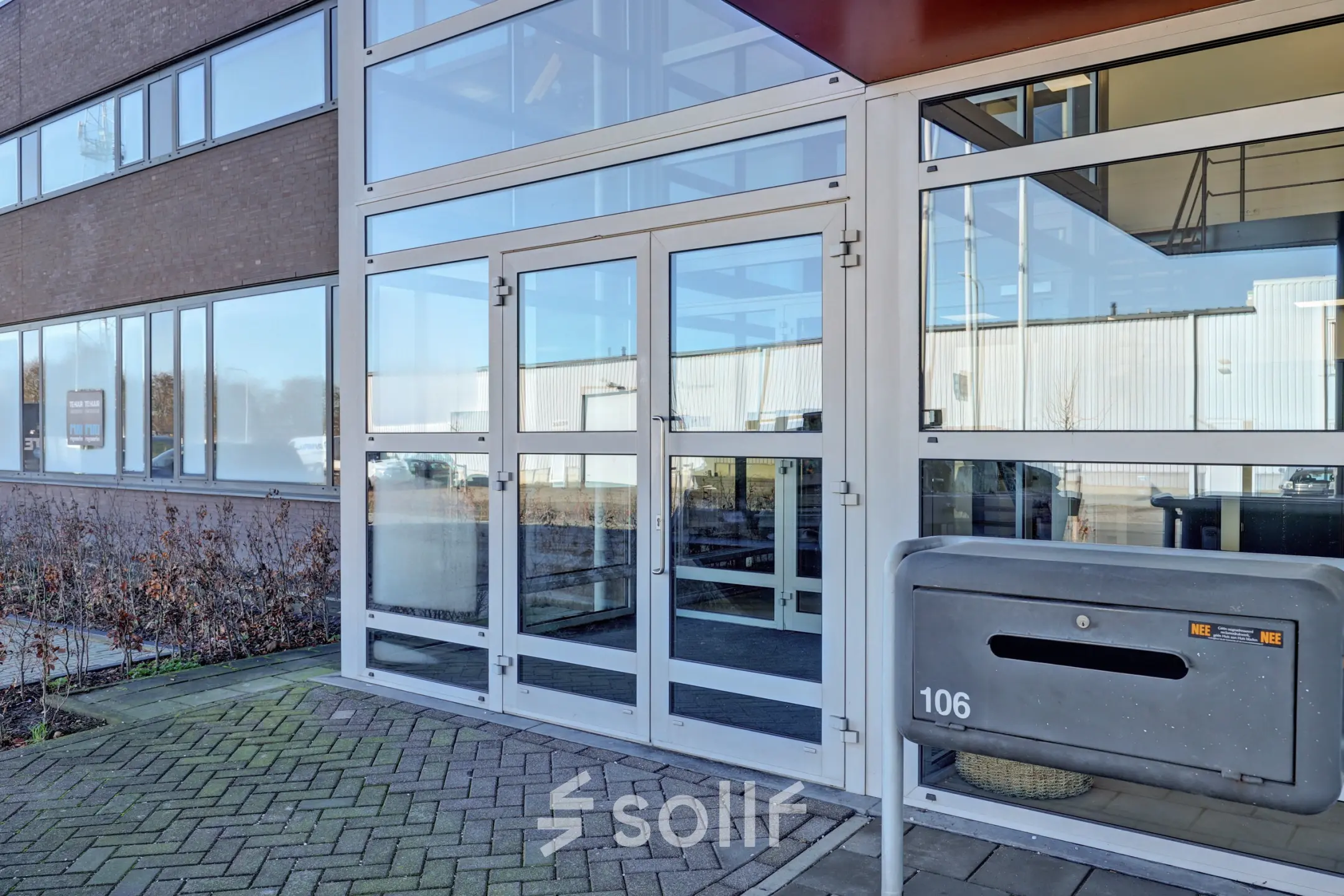 Buitenkant van een modern kantoorpand gelegen aan het Fischerpad 106 in Sittard, met glazen entree en ruime parkeerplaats. Ideale plek om kantoorruimte te huren.