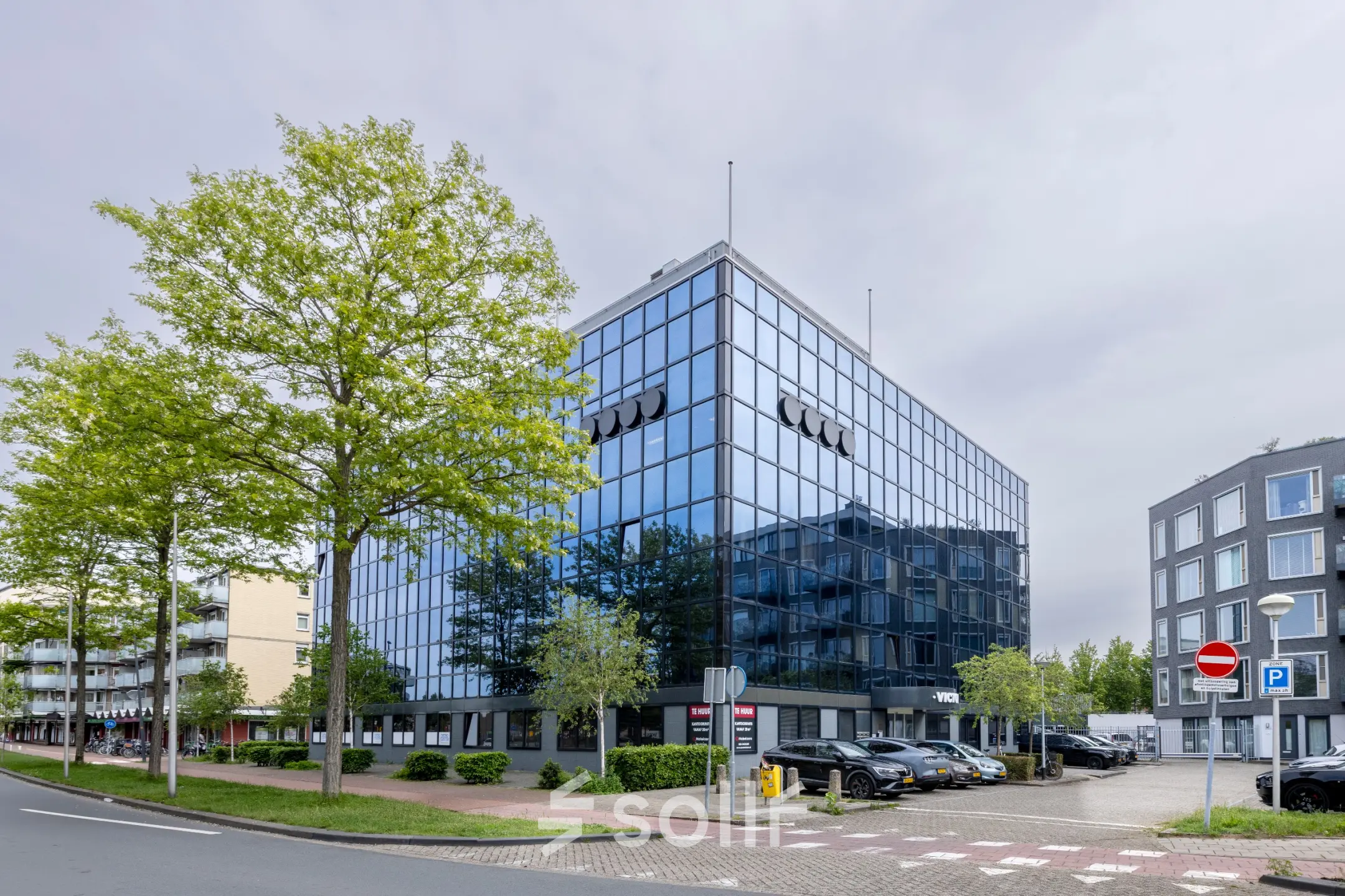 Modern kantoorpand aan de Curieweg 9 in Spijkenisse met een strakke glazen gevel en parkeermogelijkheden, ideaal voor wie kantoorruimte wil huren.