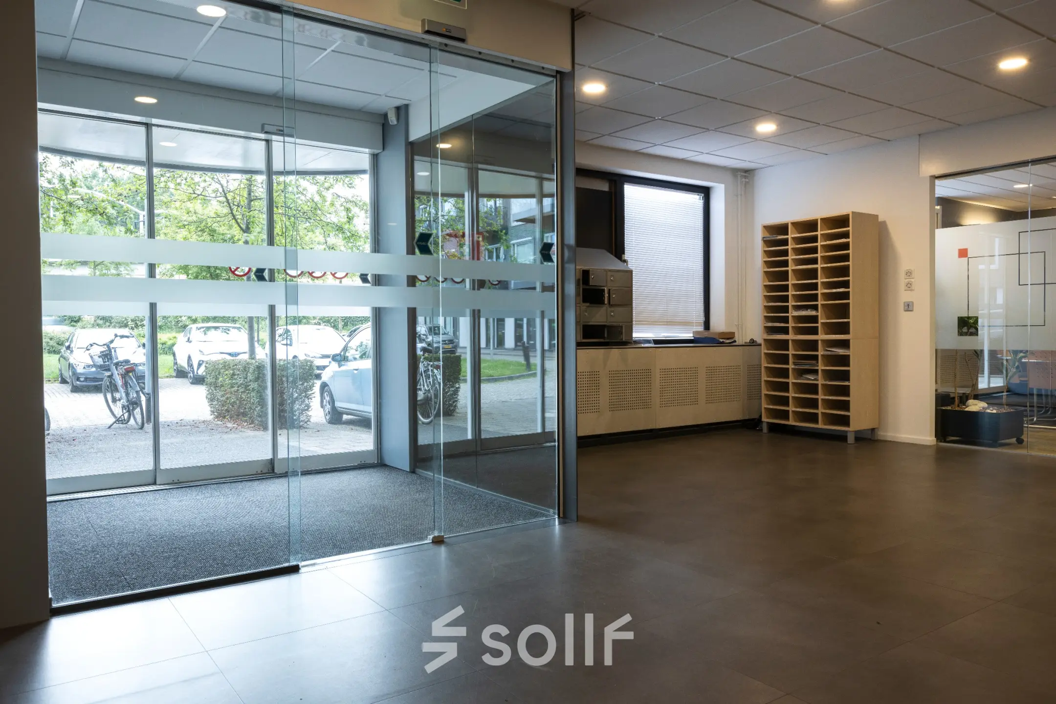 Ingang van een kantoorpand op Curieweg 9, Spijkenisse. Moderne glazen schuifdeuren en een overzichtelijke opstelling zorgen voor een uitnodigende entree voor wie kantoorruimte wil huren.