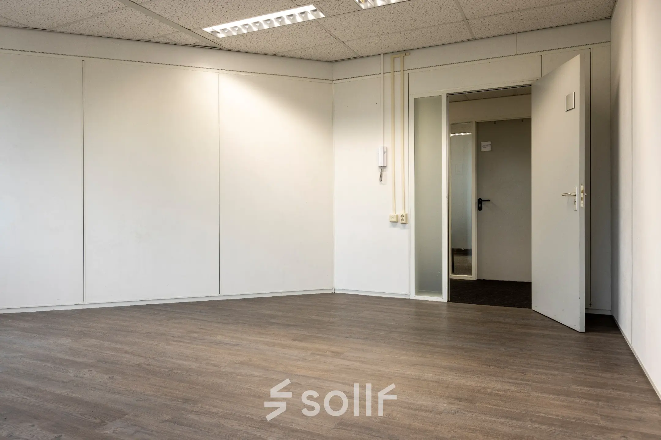 Lege kantoorruimte met houten vloer en glazen deur op Curieweg 9, Spijkenisse. Geschikt voor het huren van een veelzijdige werkplek.