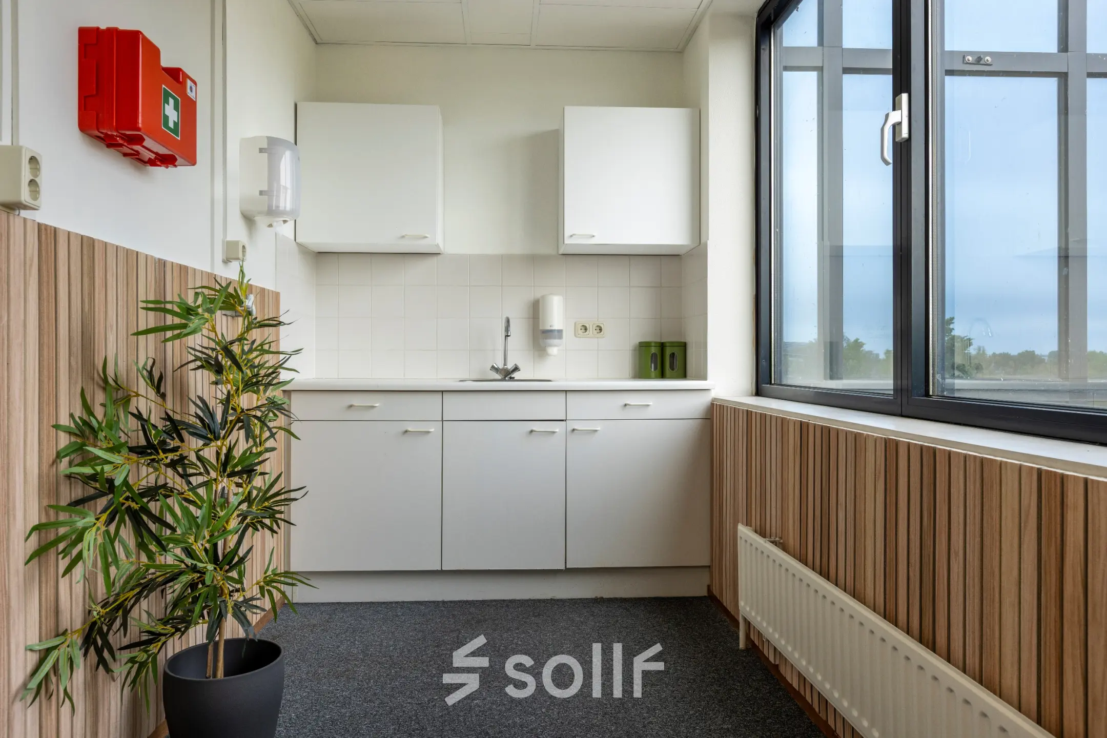 Compacte kitchenette in het kantoorpand aan Curieweg 9, Spijkenisse, met houten details en uitzicht naar buiten. Ideaal voor een kleine pauzeruimte bij het huren van een kantoorruimte.
