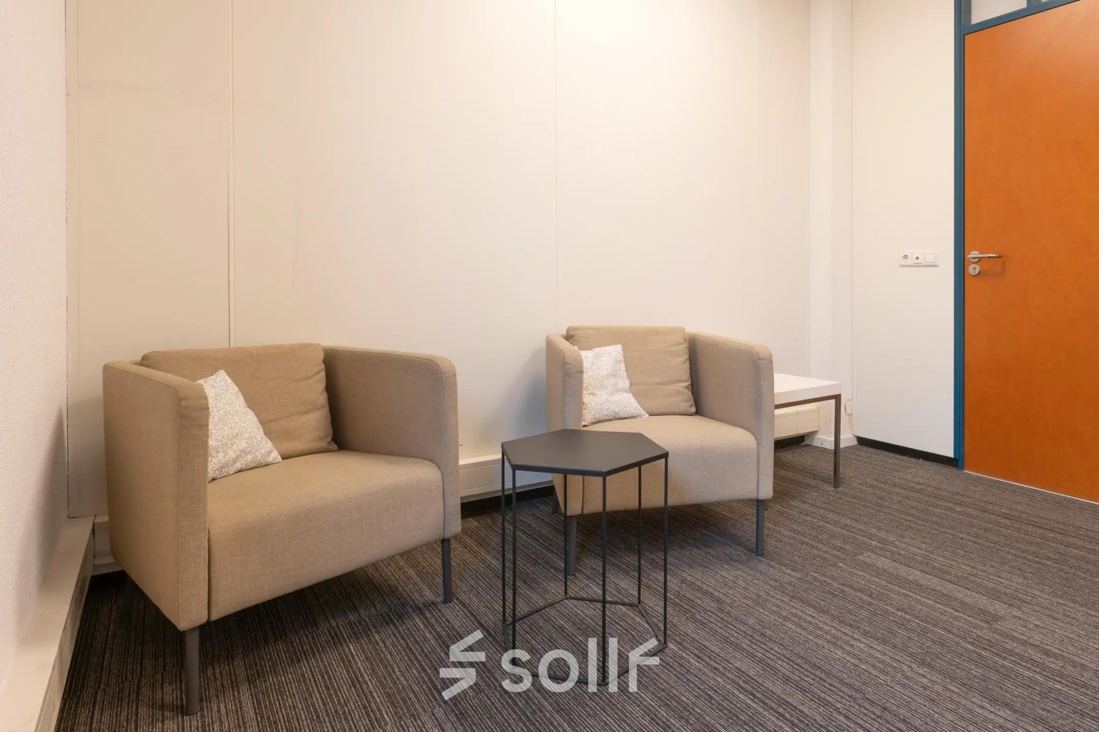 Stijlvolle kantoorruimte huren op Curieweg 9 in Spijkenisse met moderne, minimalistische inrichting, voorzien van twee comfortabele fauteuils, een bijzettafel en kussenaccenten.