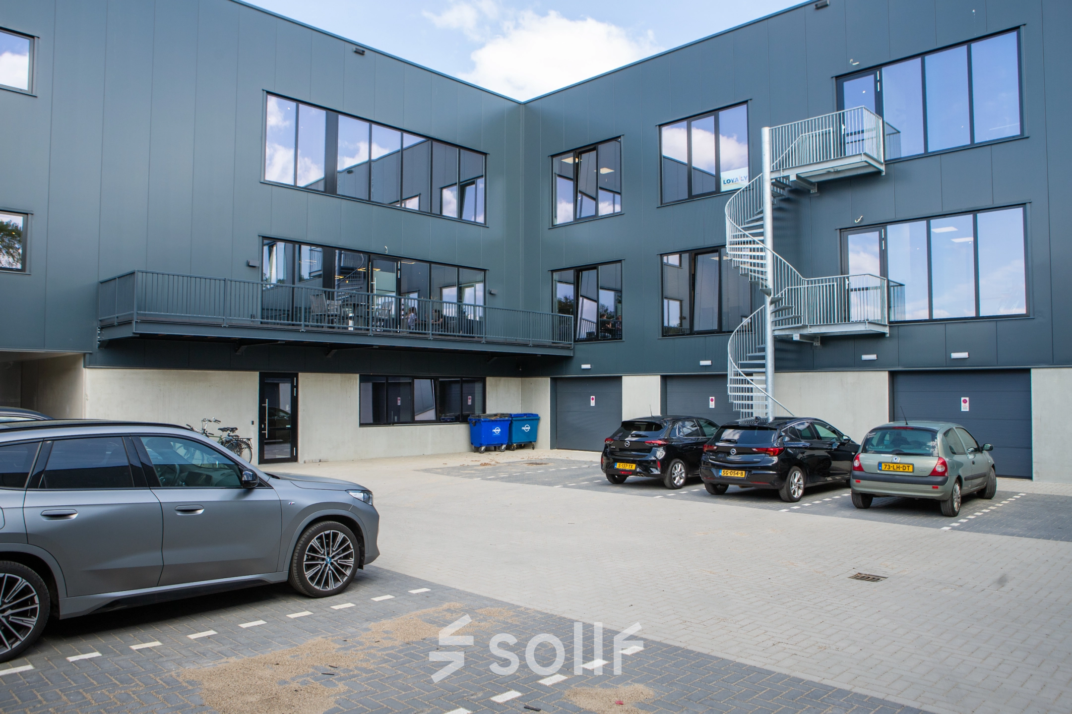 Buitenaanzicht van een modern kantoorpand op Kapitein Rondairestraat 8 in Tilburg met meerdere parkeerplaatsen voor de deur.