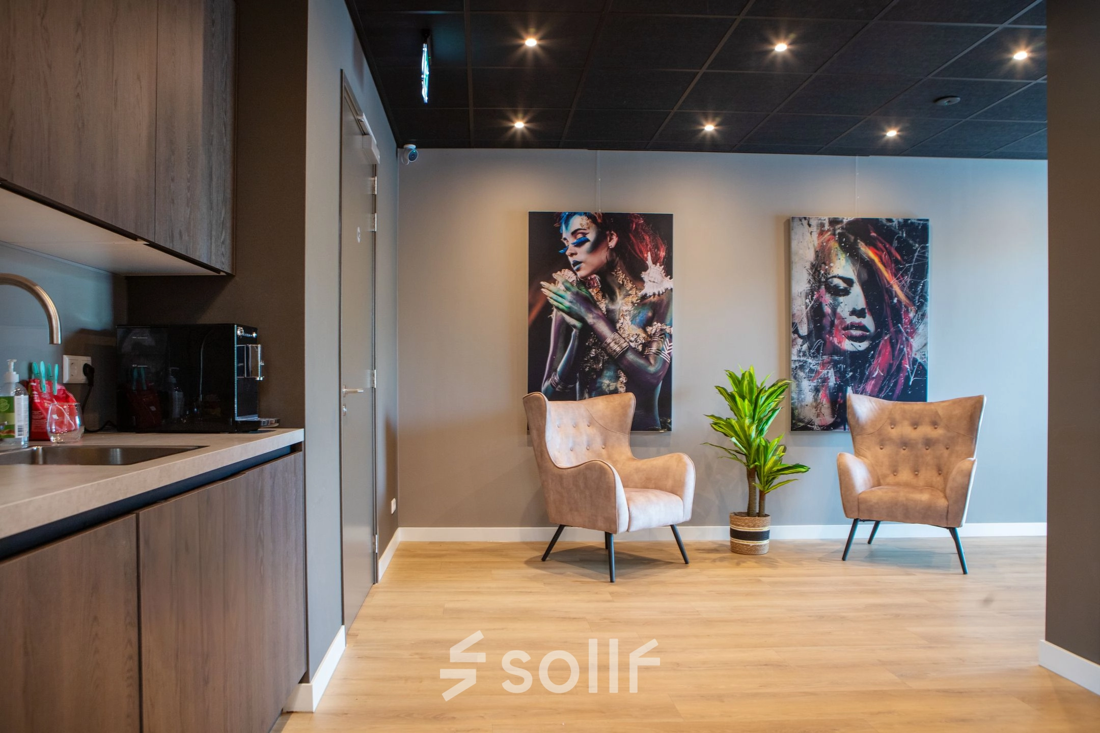Kantoorruimte met moderne inrichting aan de Kapitein Rondairestraat 8 in Tilburg, voorzien van comfortabele fauteuils, kunst aan de muur en een klein keukenblok. Ideaal om een kantoor te huren.