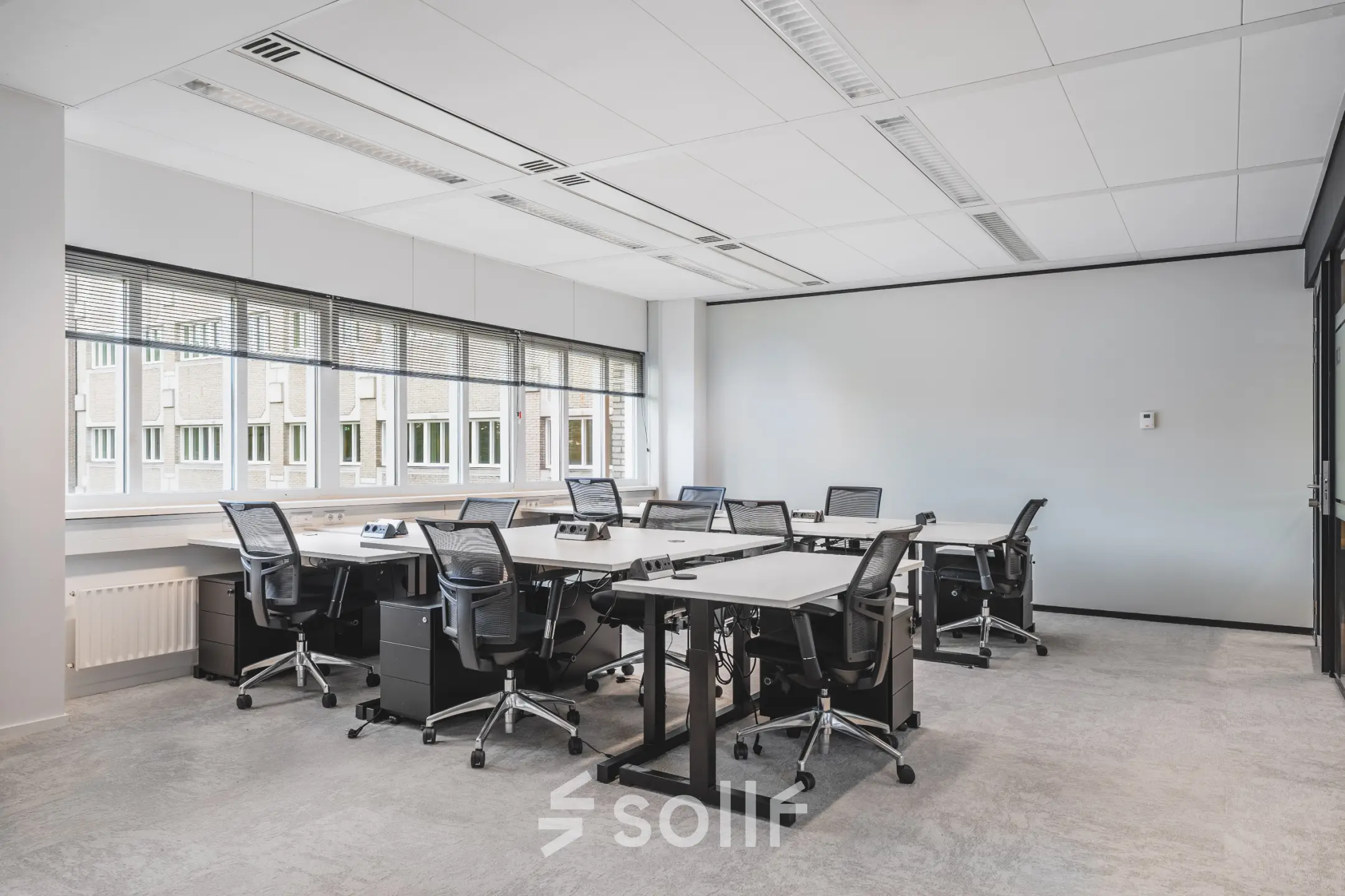 Kantoorruimte met moderne bureaus en stoelen in een lichte ruimte bij Utrecht Centraal Station. Grote ramen zorgen voor natuurlijk licht. Ideaal voor huur van werkplekken.