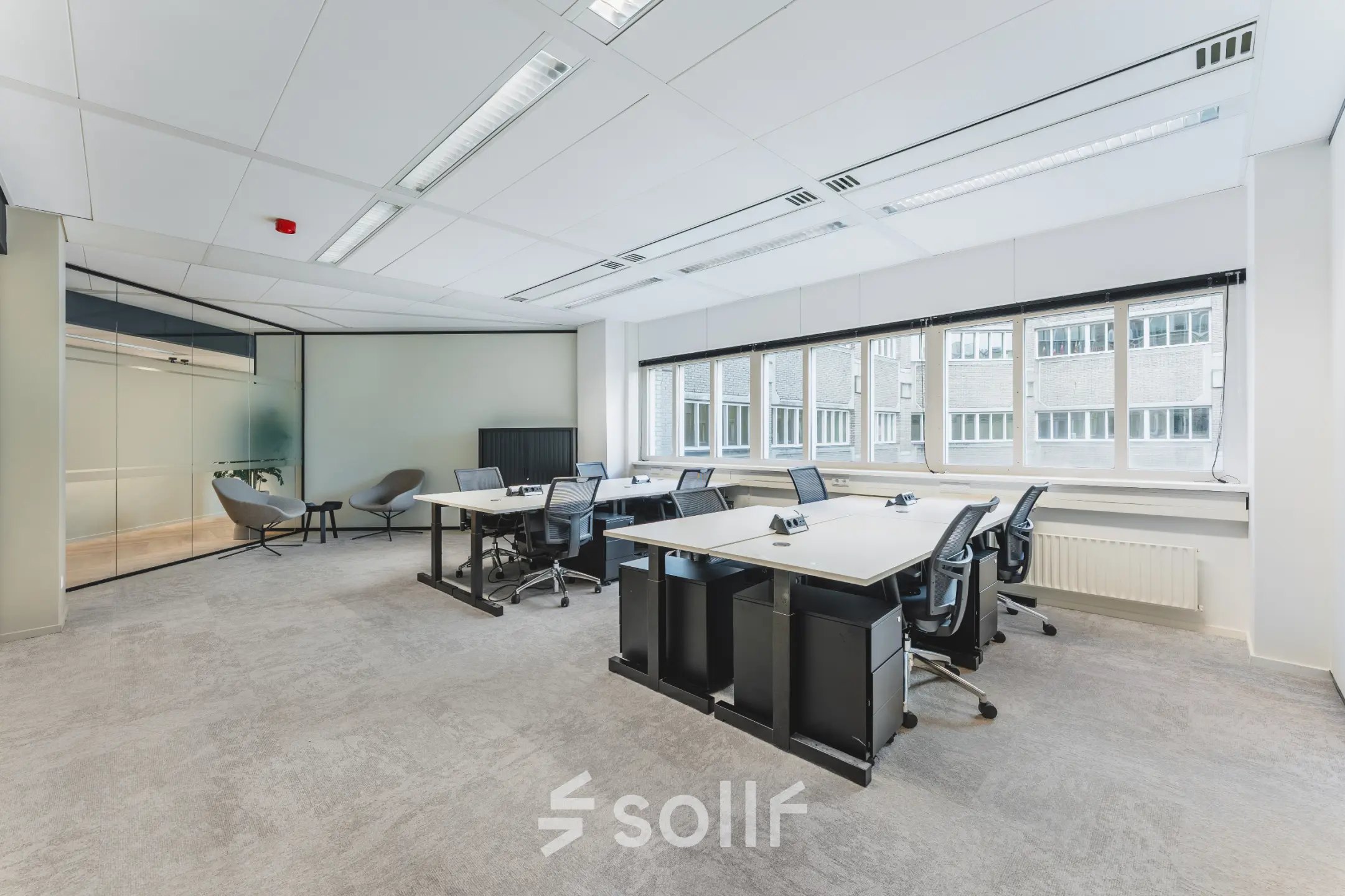 Lichte en moderne kantoorruimte met uitzicht op een gebouw, voorzien van bureaus en stoelen op Leidseveer 2-10, Utrecht Centraal Station, ideaal om te huren.