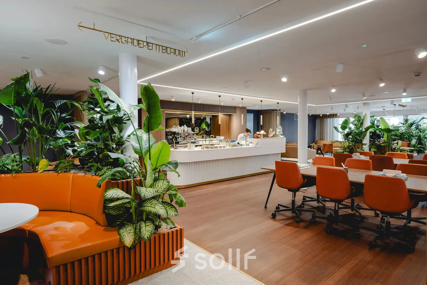 Moderne en groene kantoorruimte te huur op Moreelsepark 1, Utrecht Centraal Station, met oranje stoelen en een café-achtige sfeer.