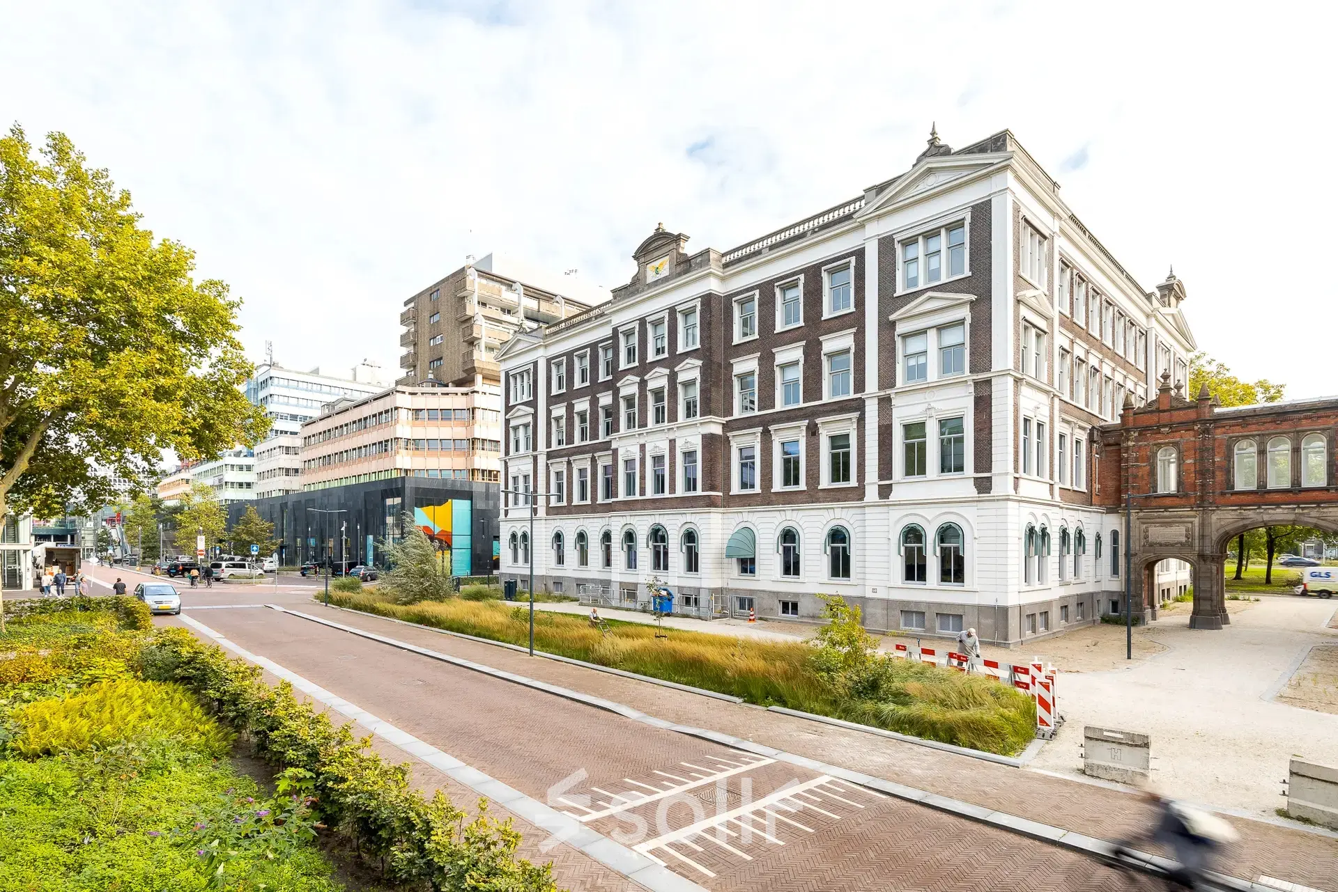 Klassiek vier verdiepingen hoog kantoorpand aan Moreelsepark 1, Utrecht Centraal Station, met bakstenen en witte accenten, omgeven door groene plantsoenen en stedelijke architectuur.
